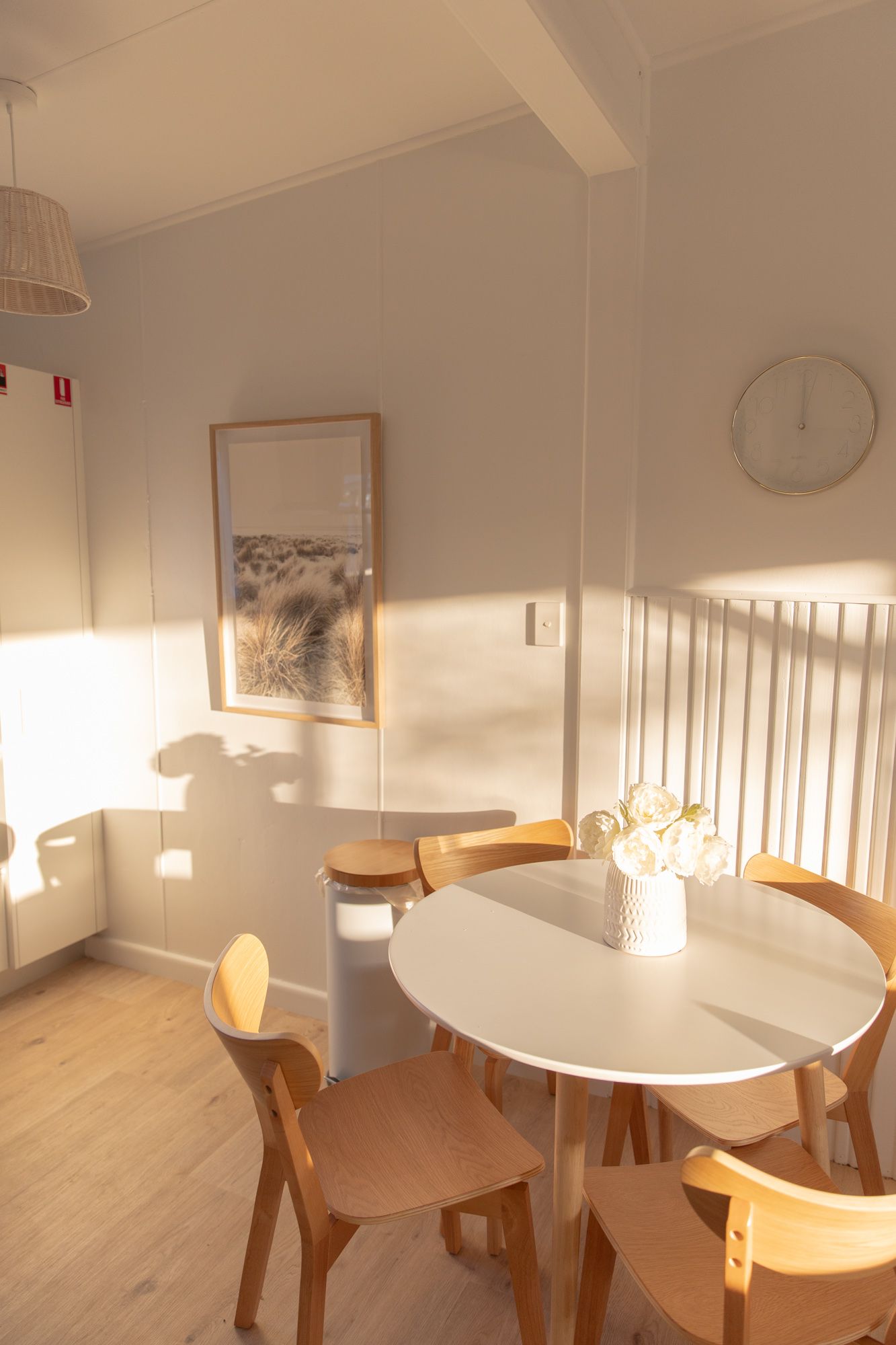 Bright dining area with white round table and wooden chairs in natural light.