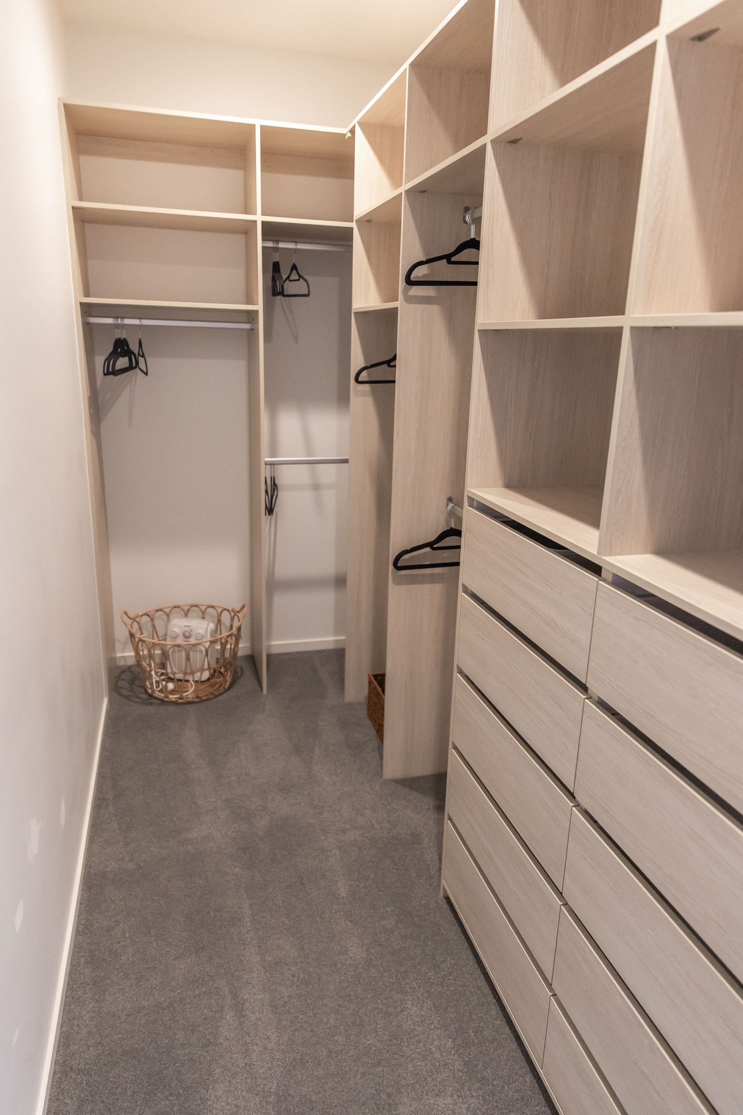 Spacious walk-in closet with white built-in shelving and drawers.