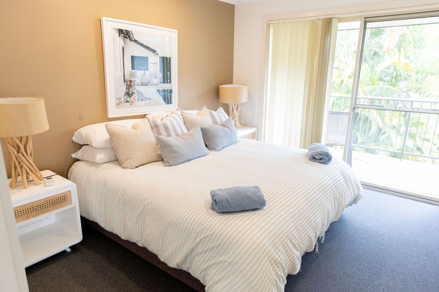 Serene bedroom with white bedding, neutral tones, and natural light streaming through windows.
