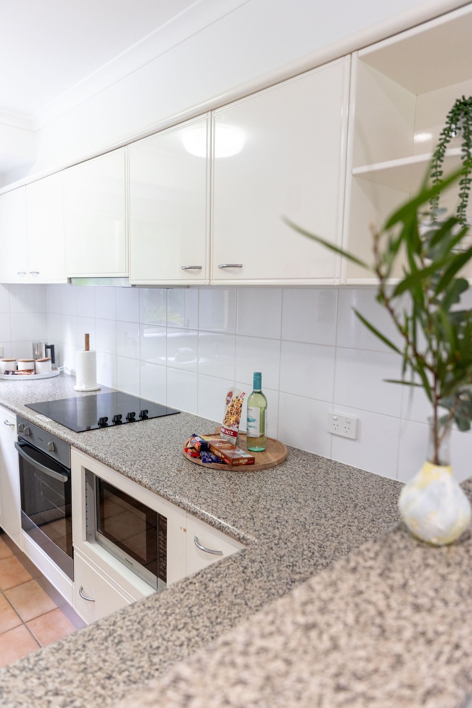 Modern white kitchen with speckled granite countertops and sleek cabinet storage.