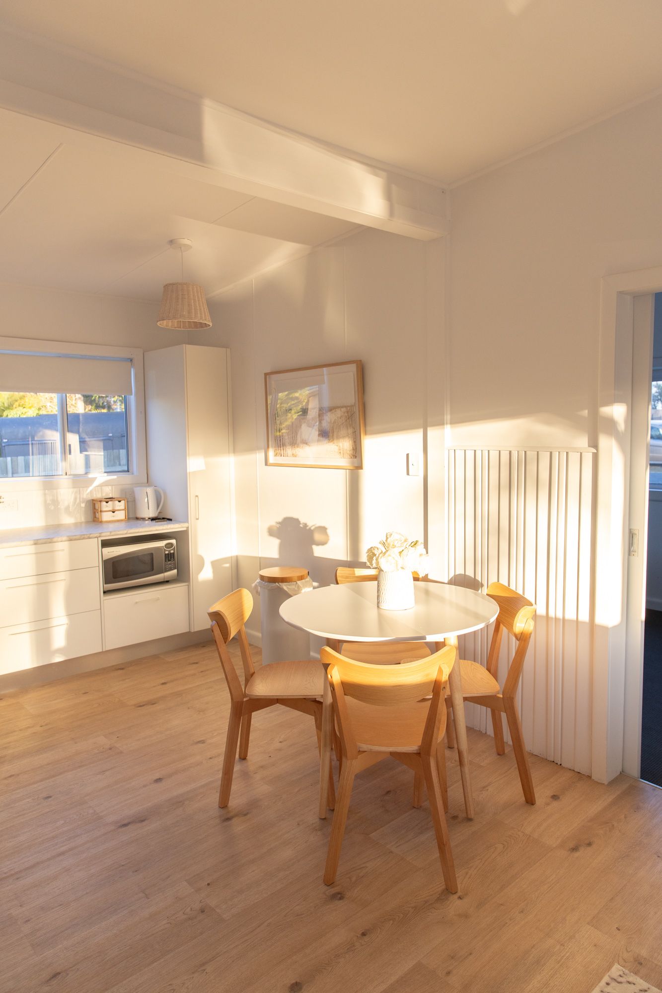 Bright dining area with wooden floors and modern round tables in an open-concept space.