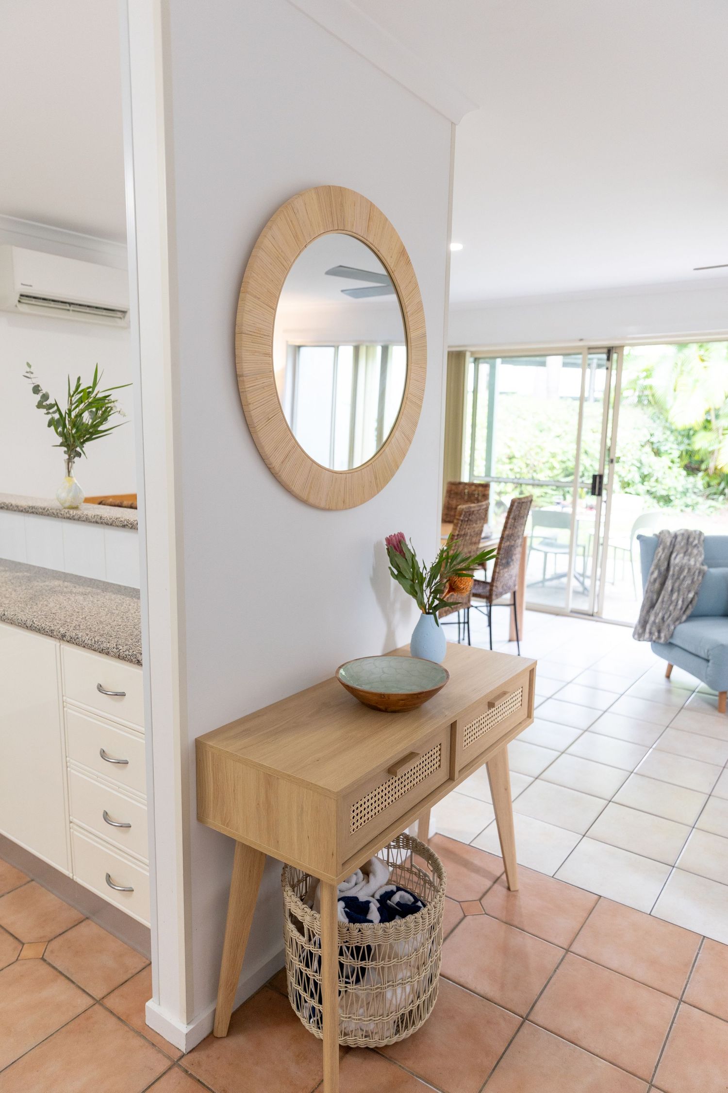 Entryway console table with round mirror and coastal decor against white walls.