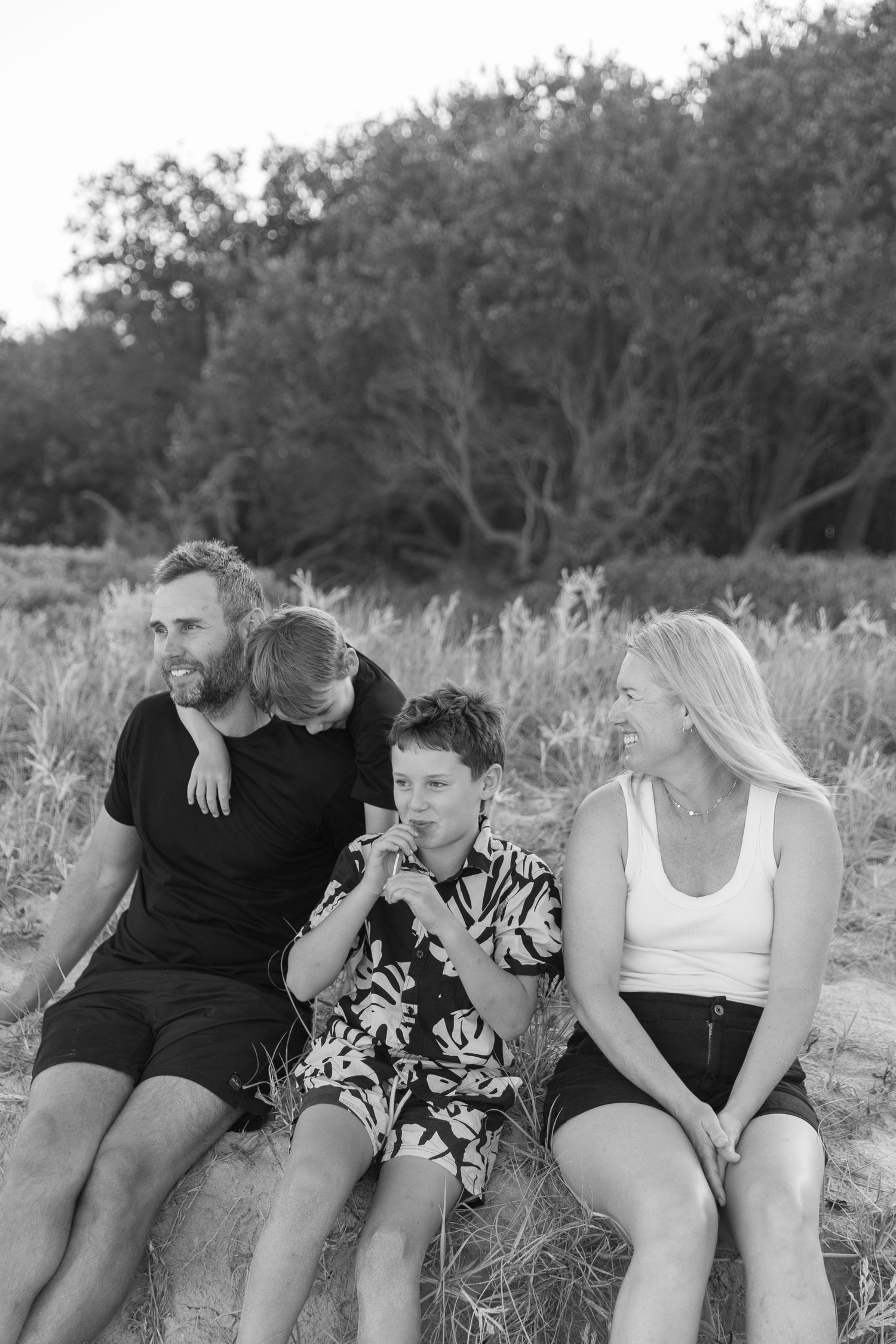 Casual family photoshoot showing playful interactions while sitting together outdoors.