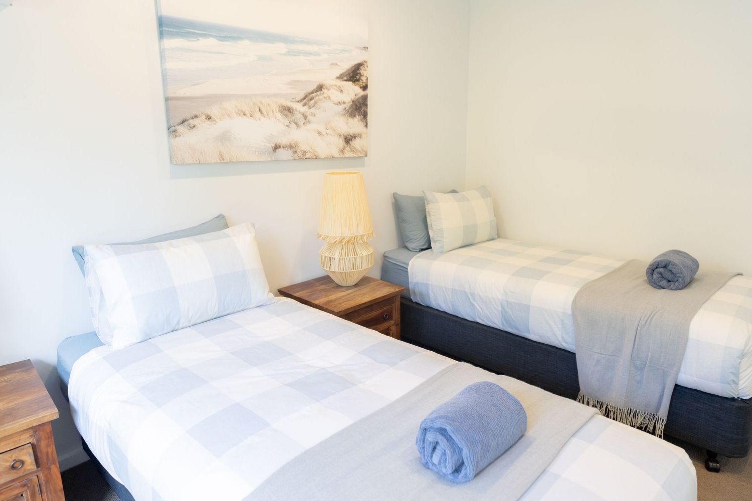 Serene bedroom with white bedding and beachy wall art.