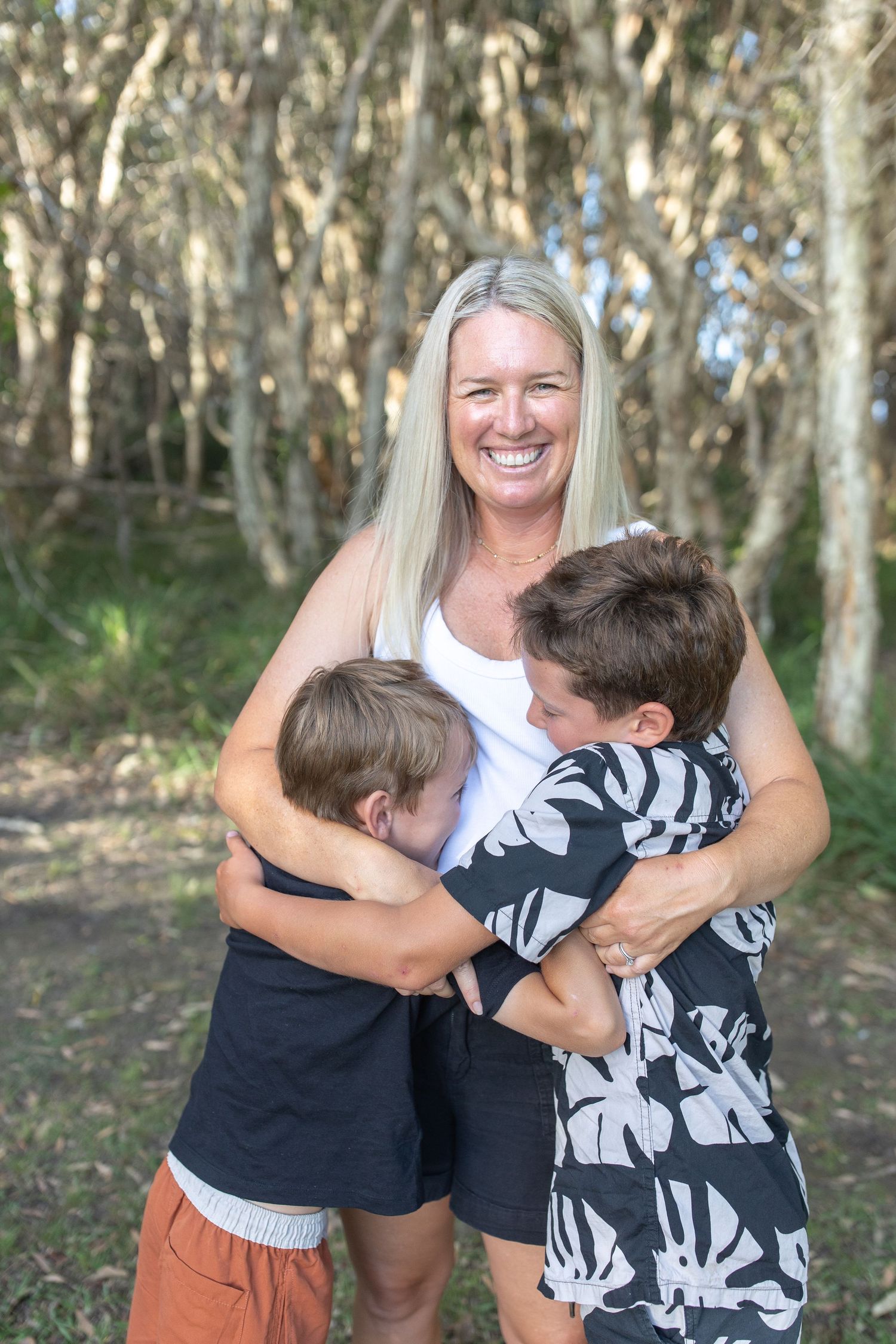 A group sharing playful embraces and laughter in a forest setting.