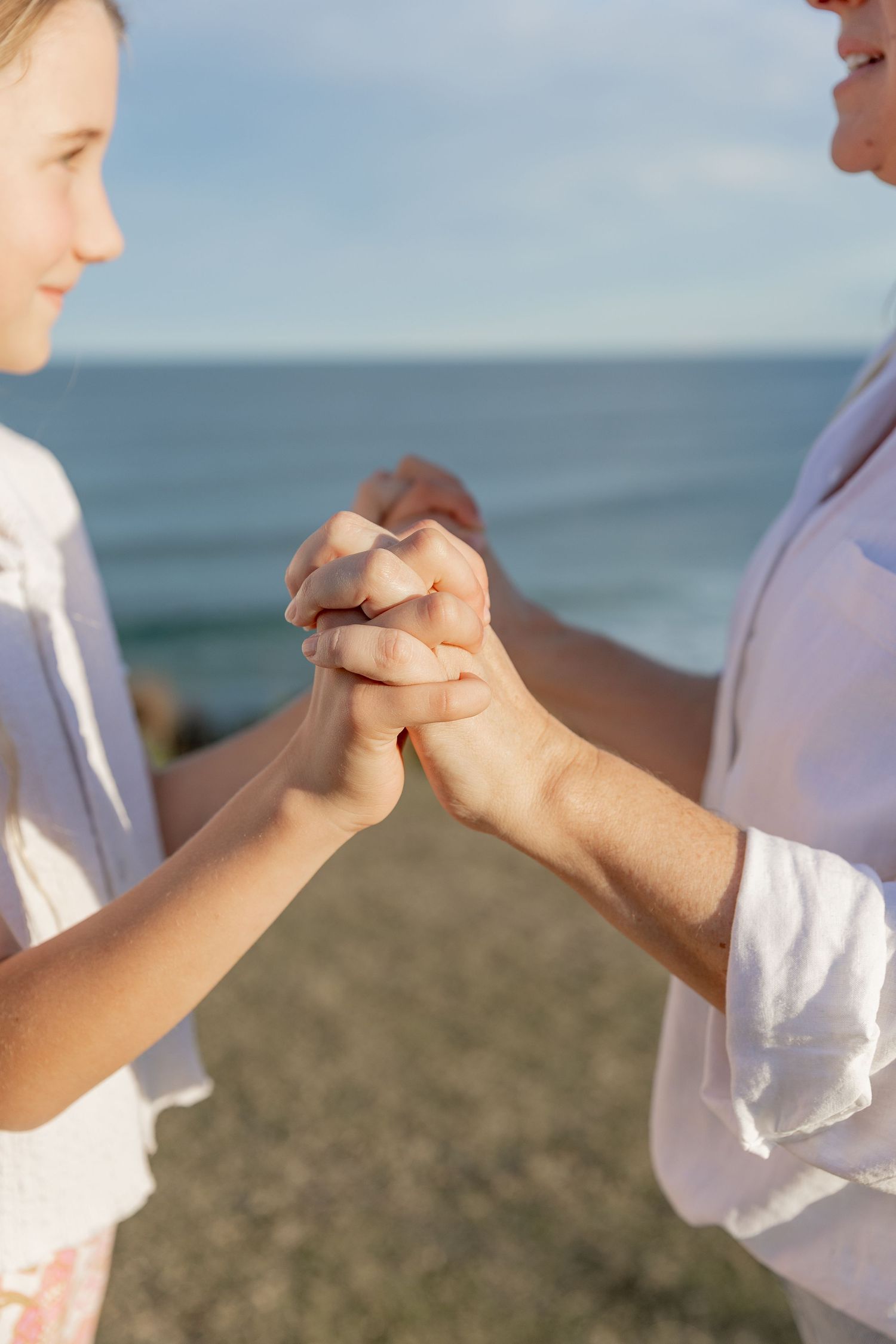 Close-up of hands clasped together against an ocean backdrop.