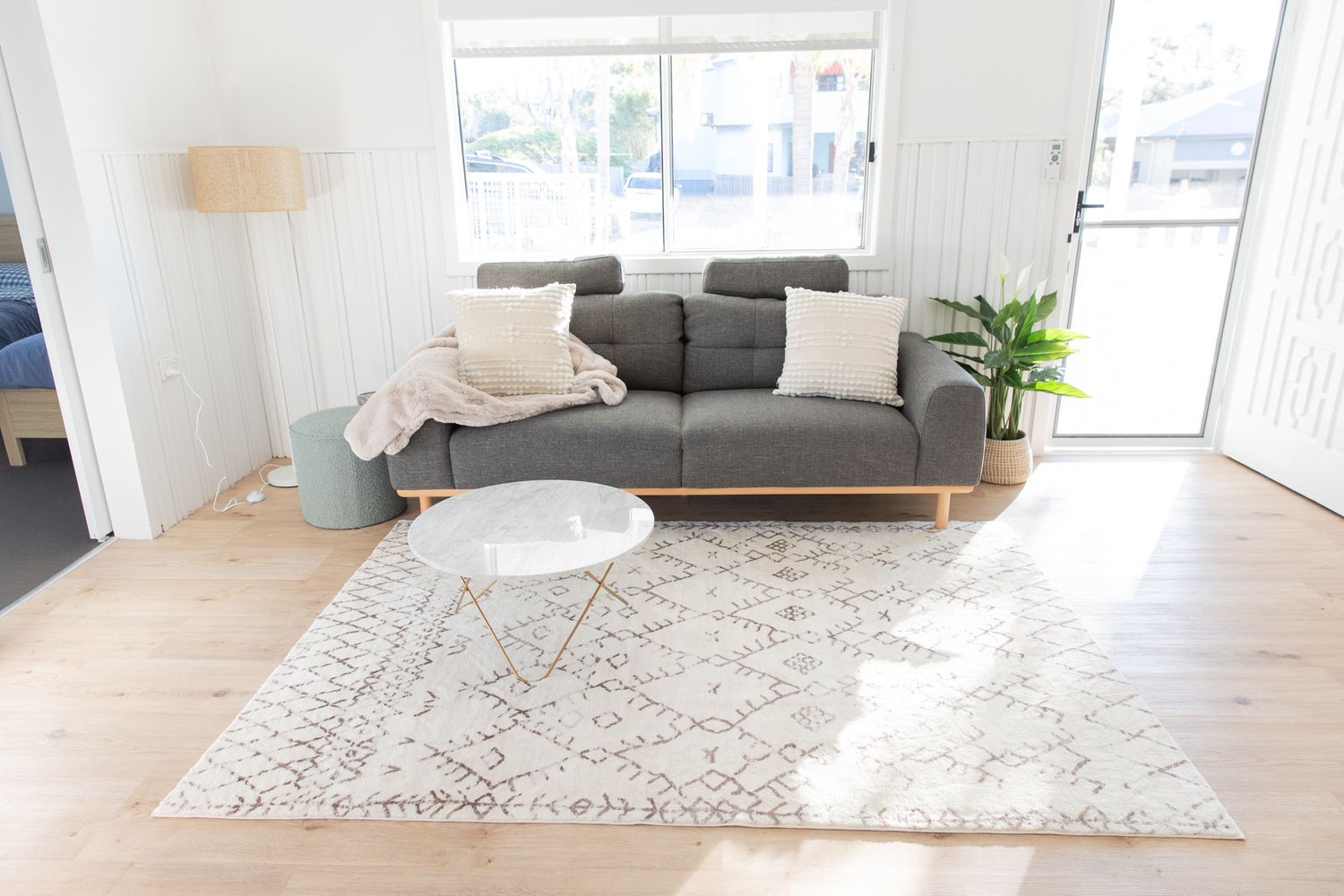 Contemporary living space with light hardwood floors and patterned area rug.