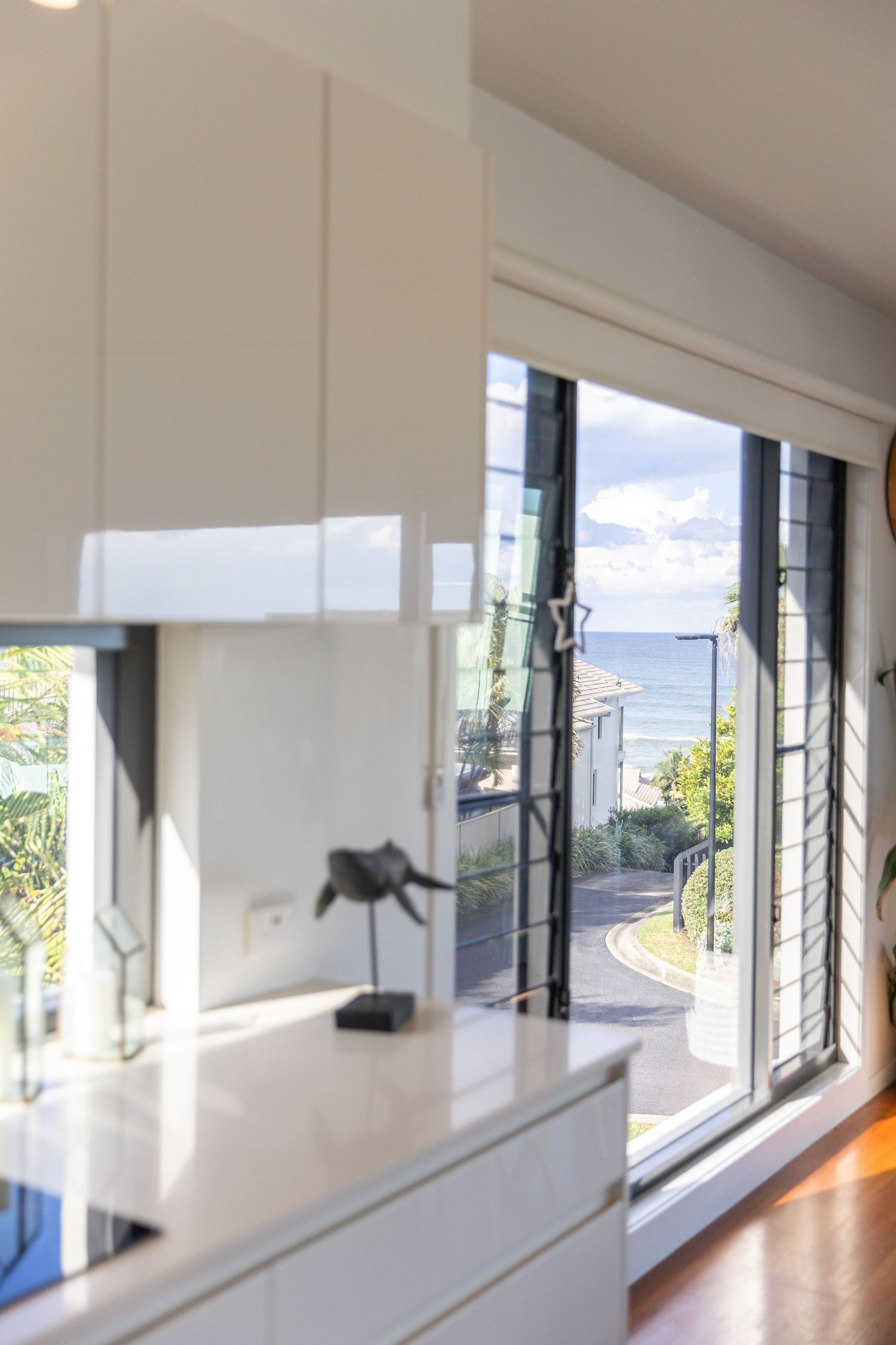 Bright white interior hallway with large windows overlooking water and modern architectural details.