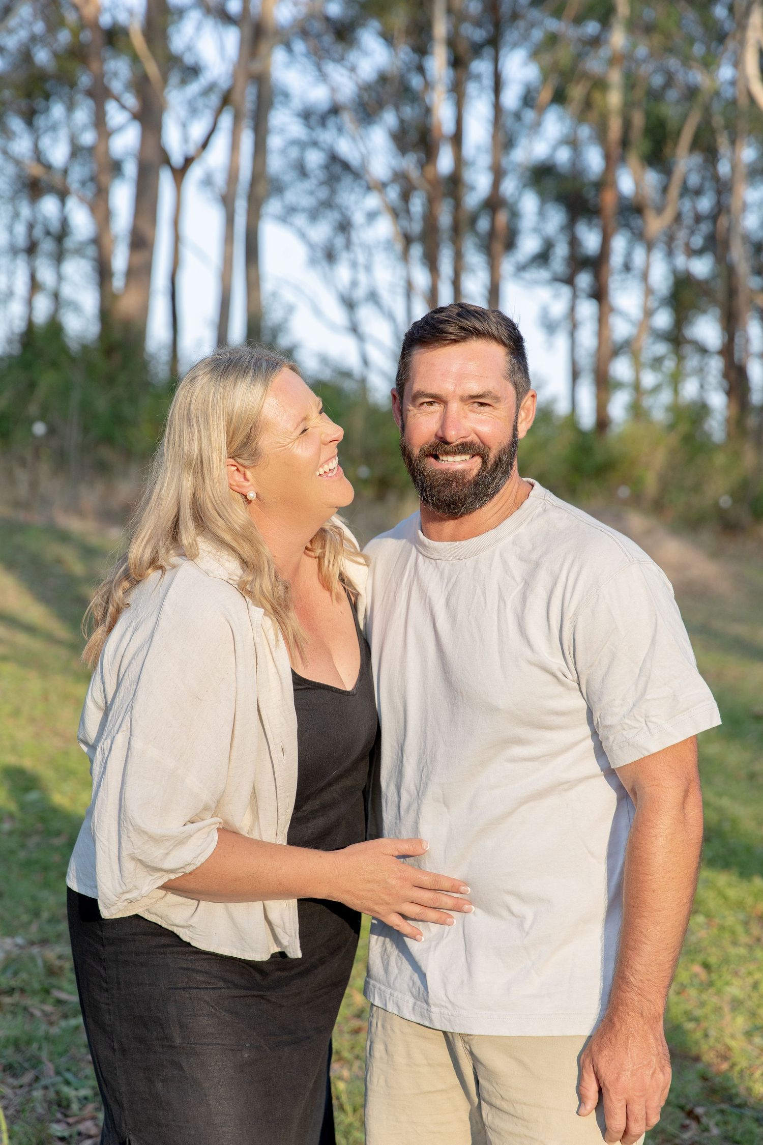 Couple shares a candid moment outdoors with eucalyptus trees in the background.