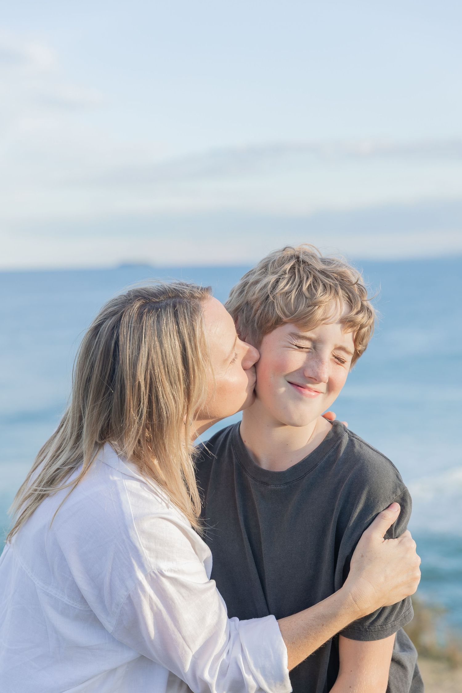 Loving moment shared between two people on a cliff overlooking the ocean.