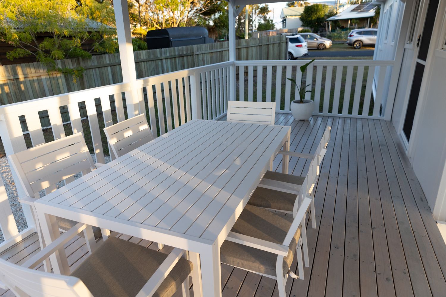 White deck furniture arranged on a covered porch with railing.