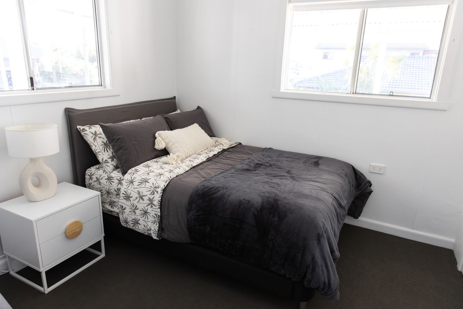 Modern bedroom featuring dark bedding and minimalist decor.