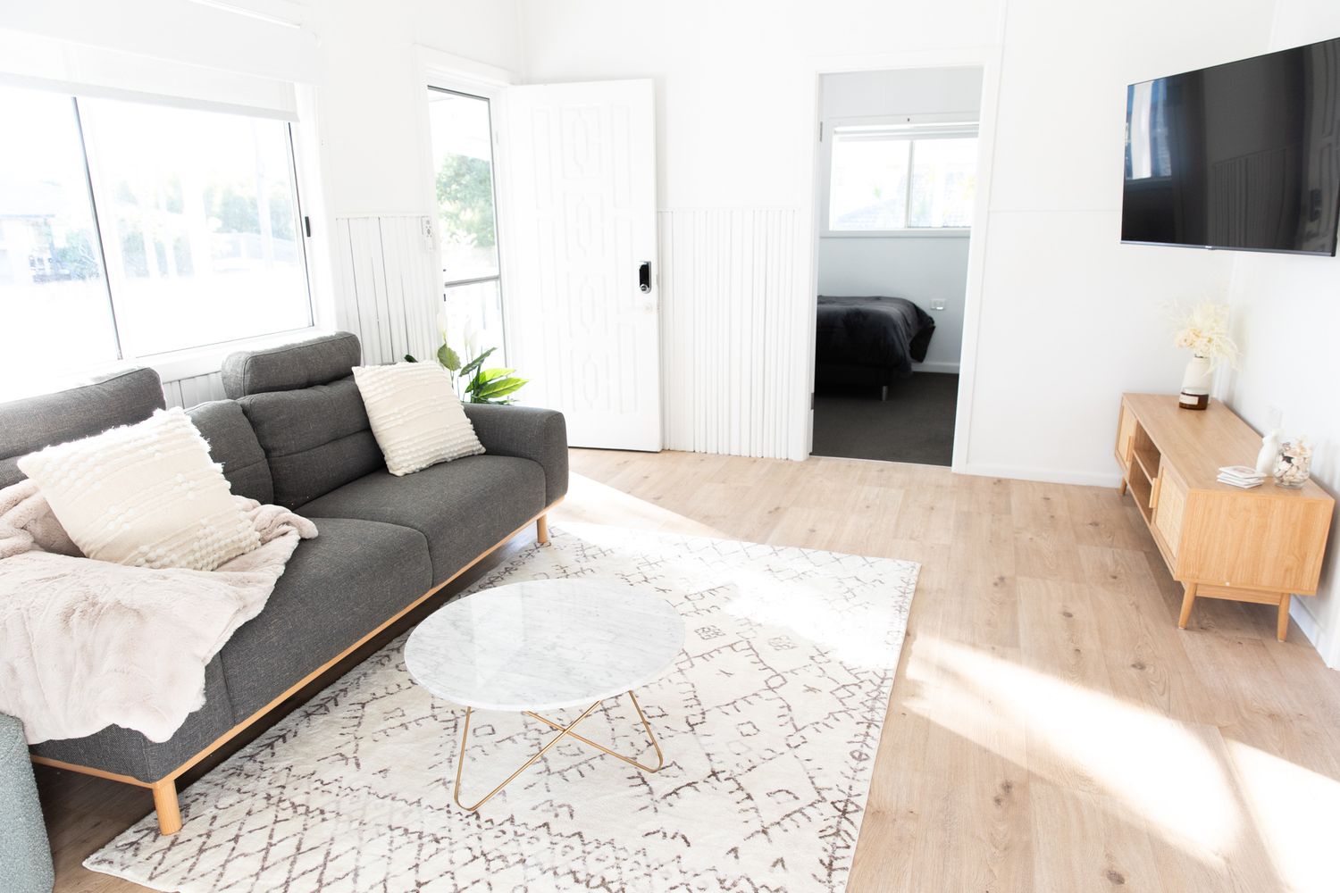 Open concept living area with Scandinavian-style furniture and geometric rug pattern.