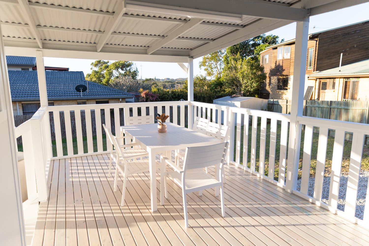 White outdoor deck furniture arranged on a spacious covered patio with railings.