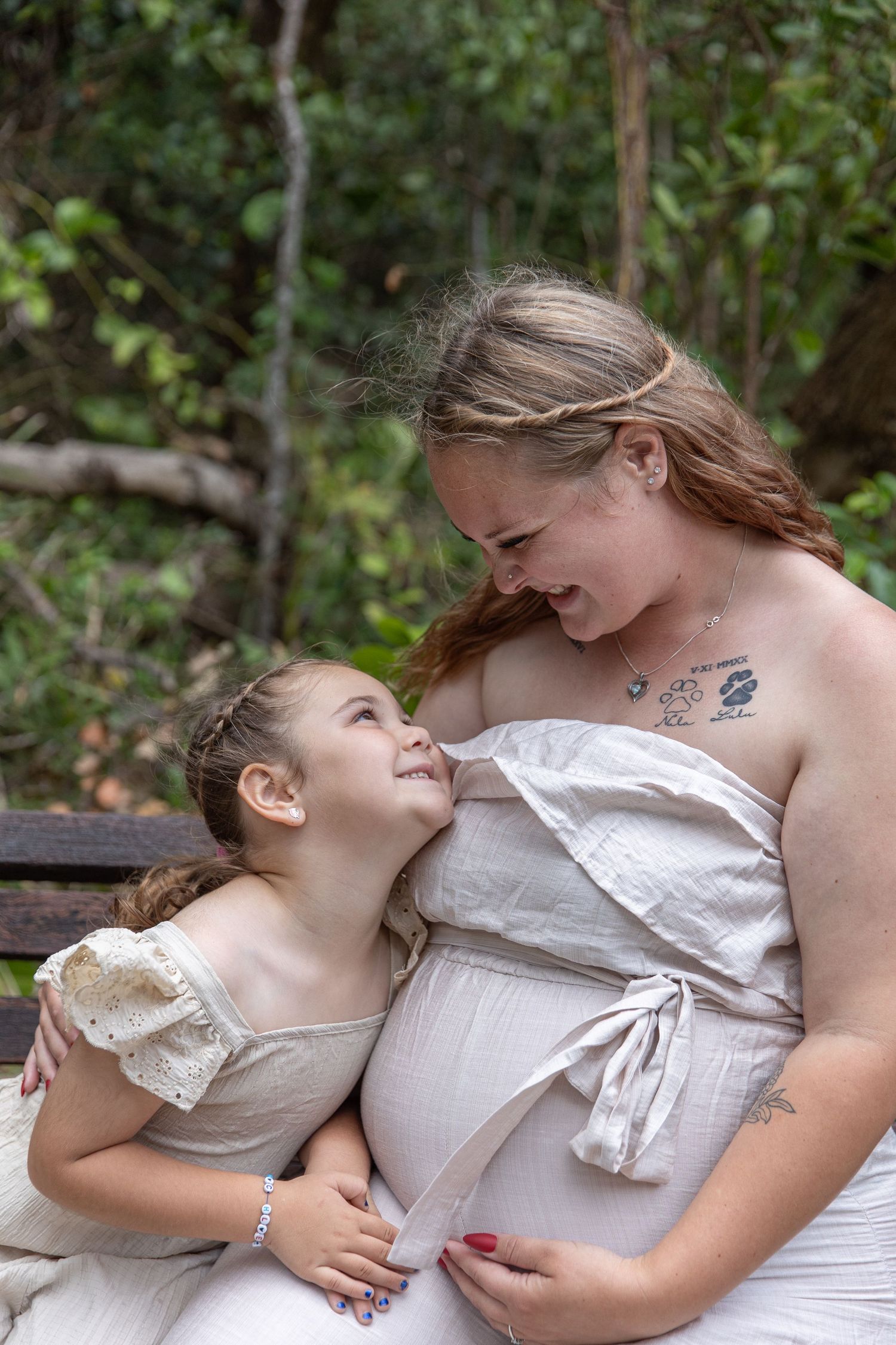 Two people in white dresses share an intimate moment together outdoors.