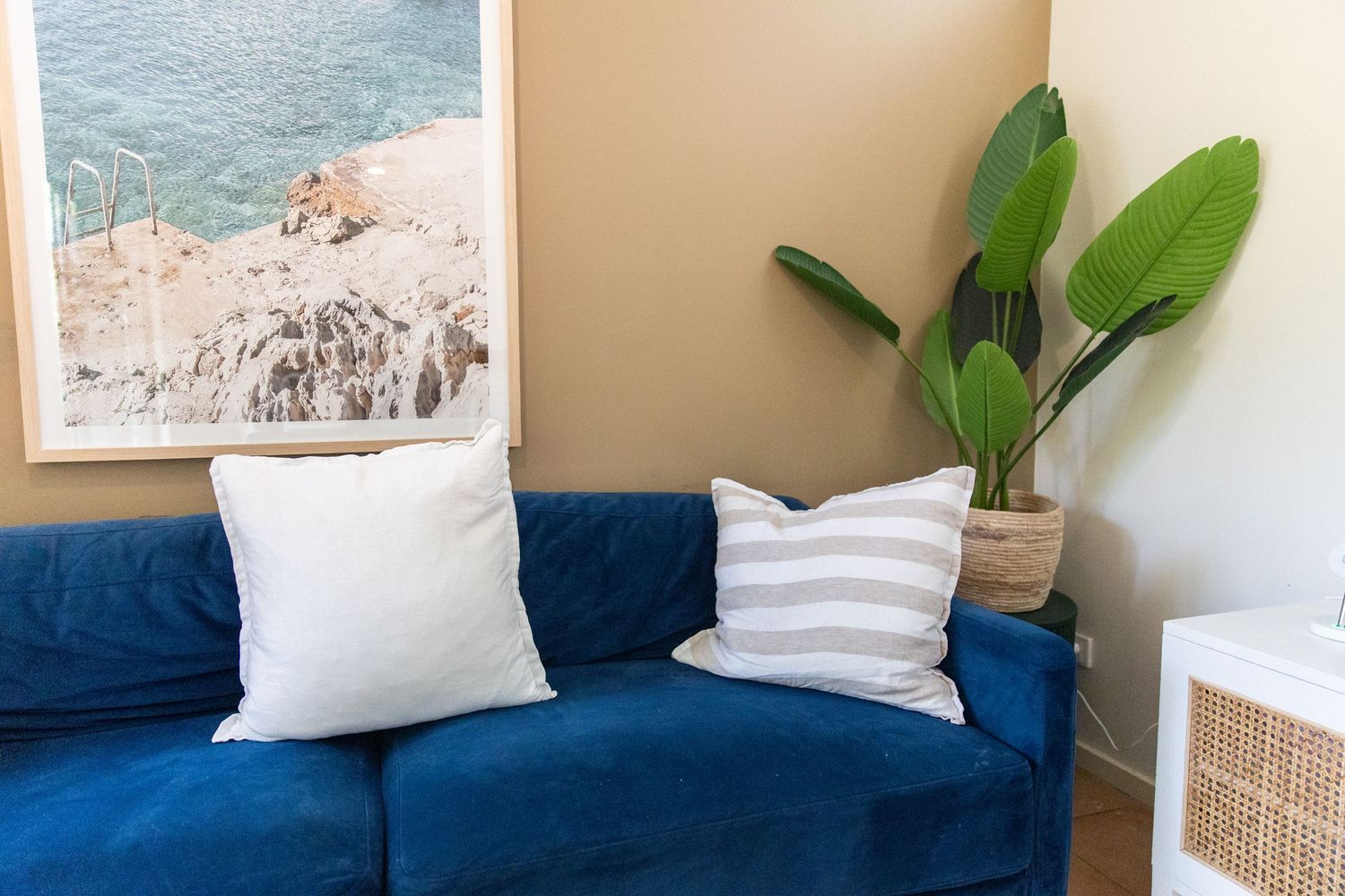 Cozy living area with blue sofa, coastal artwork, and decorative throw pillows.