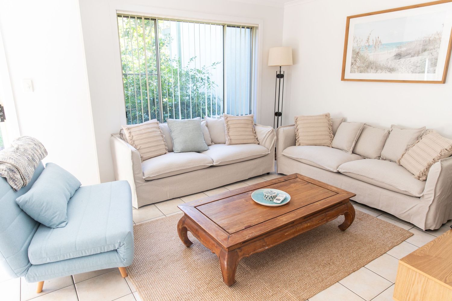 Coastal-inspired living room with beige sofas and light blue accent chair.