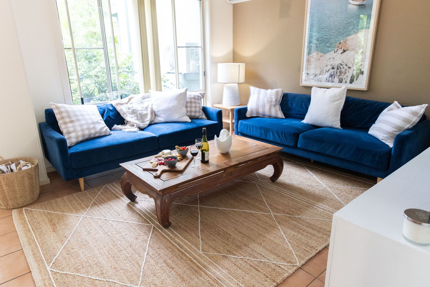 Open concept living space with blue sofa, geometric rug, and coastal-inspired decor.