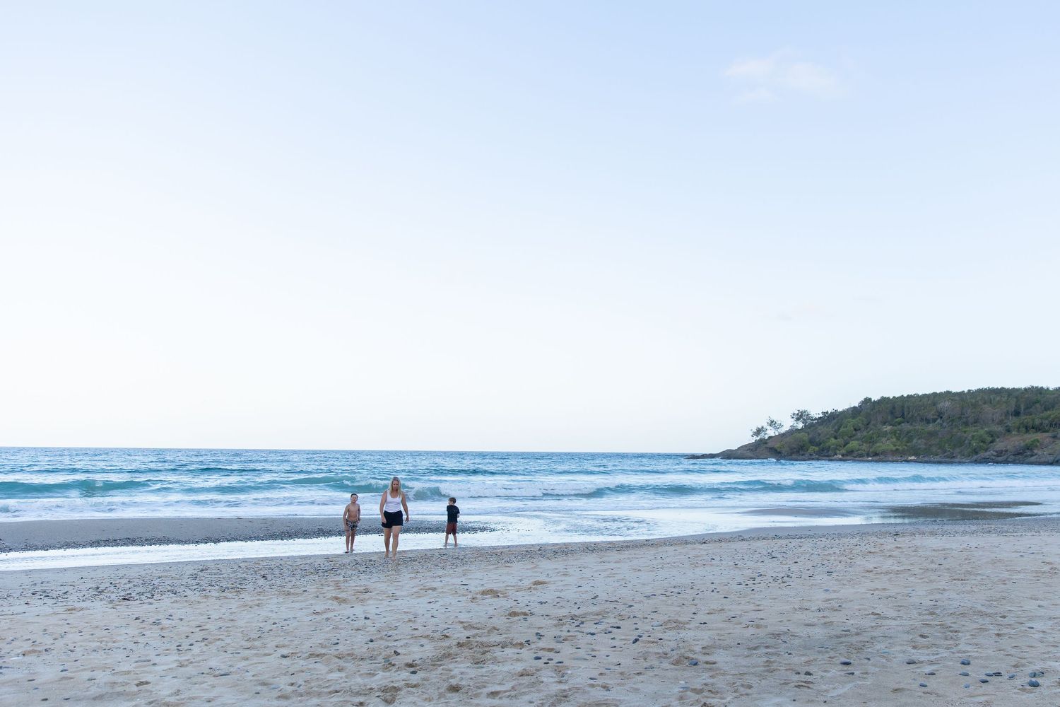 Scenic beach landscape with distant figures walking along the shoreline.