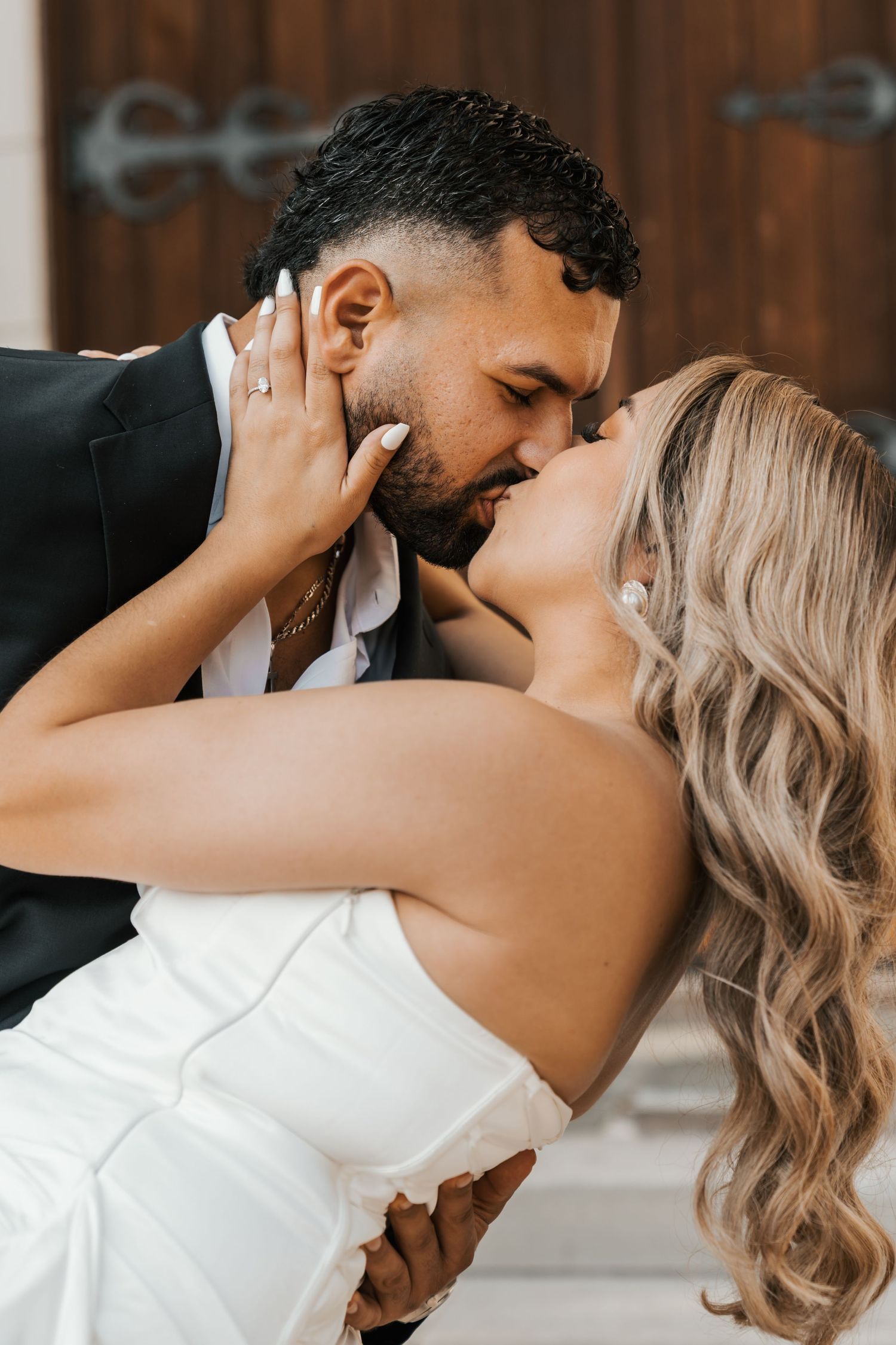A romantic wedding couple sharing an intimate dance dip pose in formal attire.