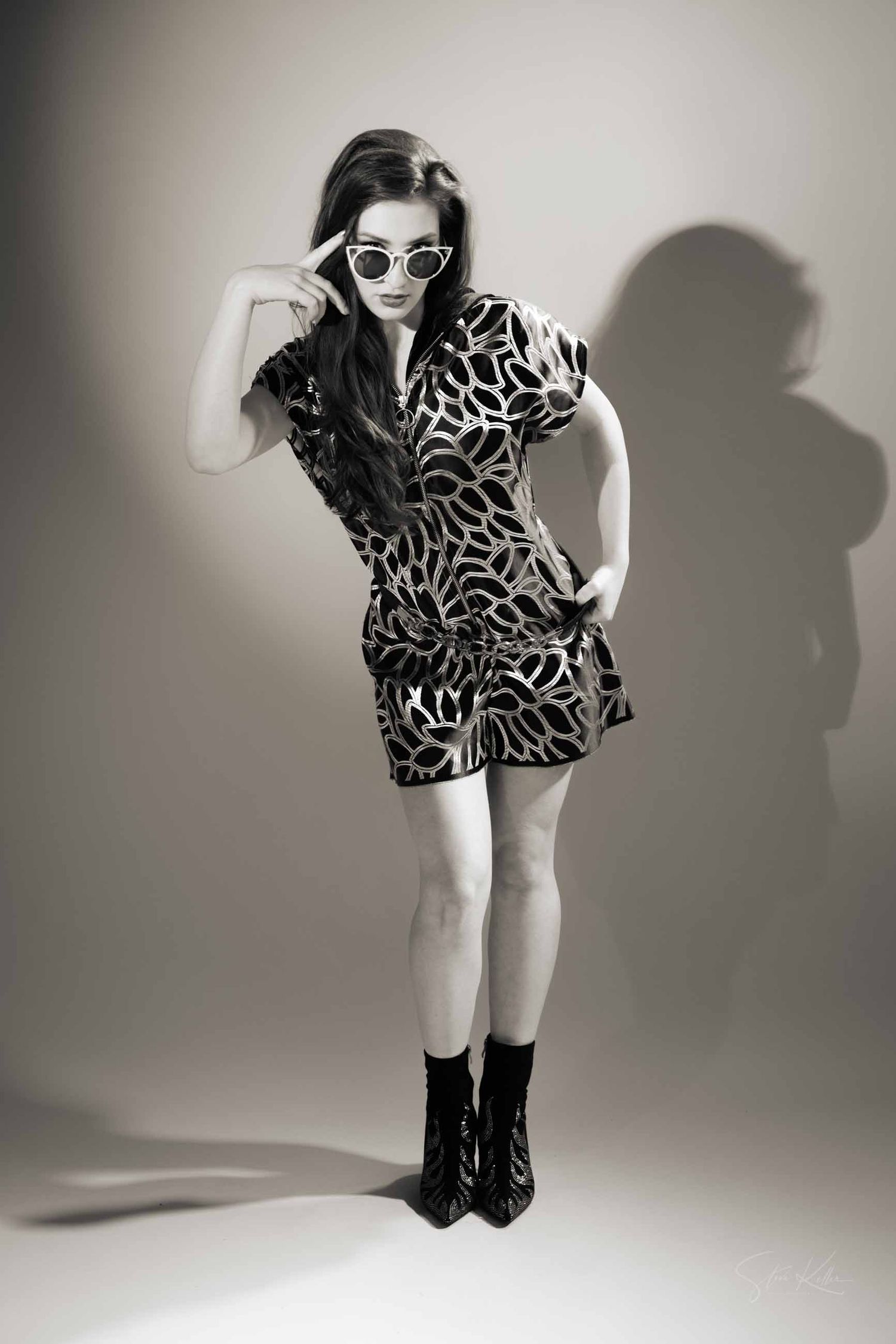 Dynamic fashion sequence showing playful poses in a printed mini dress and boots against white studio background.