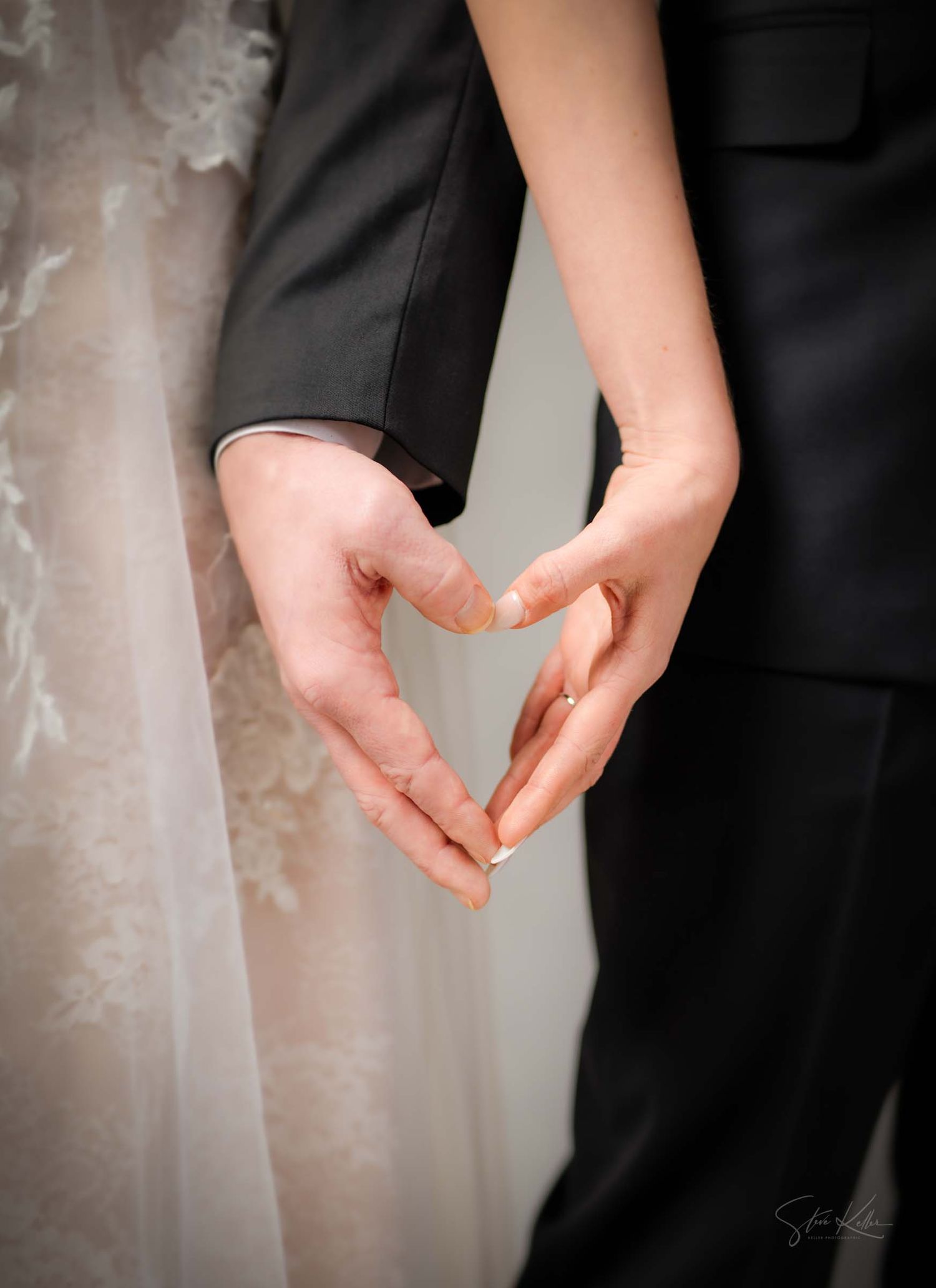 Close-up of hands exchanging wedding rings during a ceremony against a light textured background.