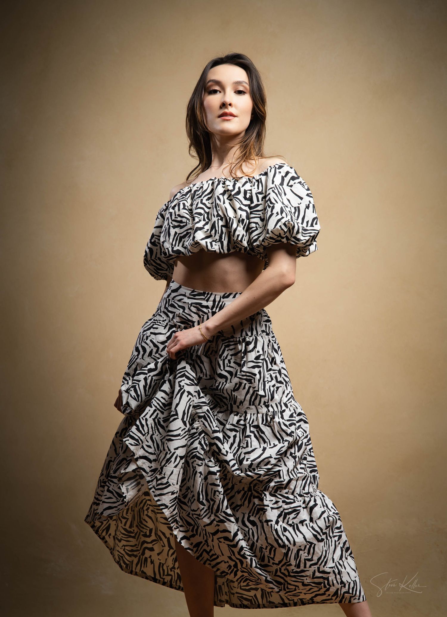 Model wearing black and white patterned two-piece dress with ruffled off-shoulder top and flared skirt.