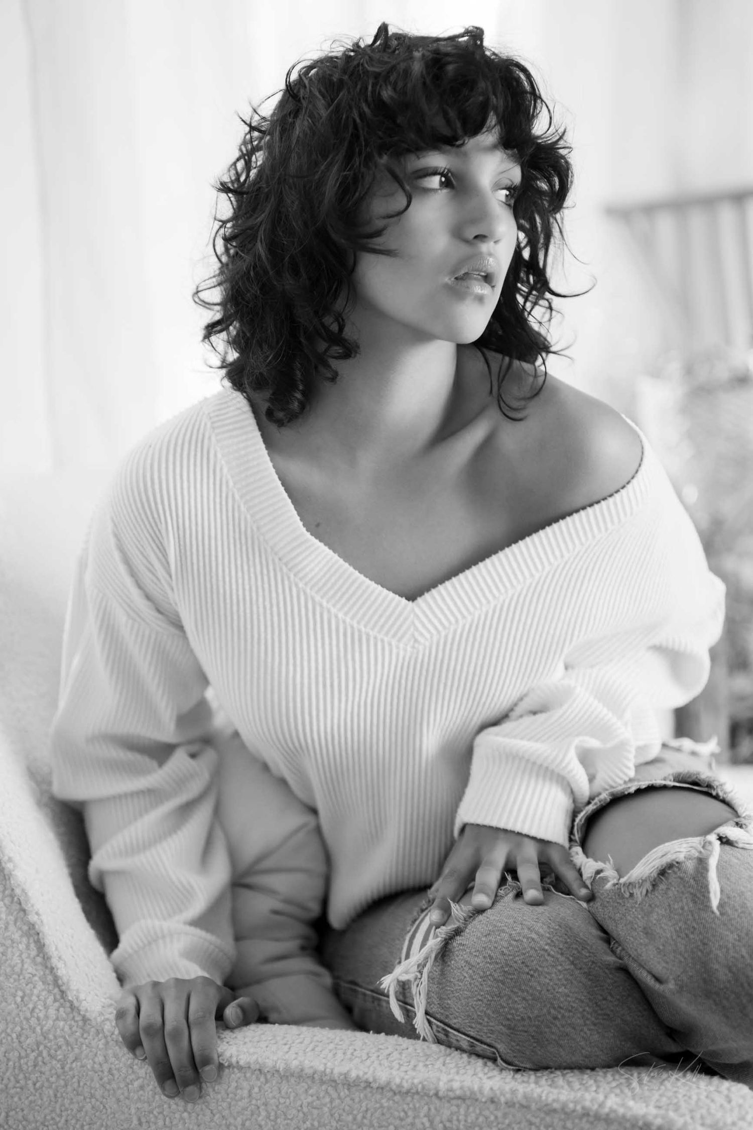 A series of black and white boudoir photos showing a person in a white sweater reclining on a soft surface.