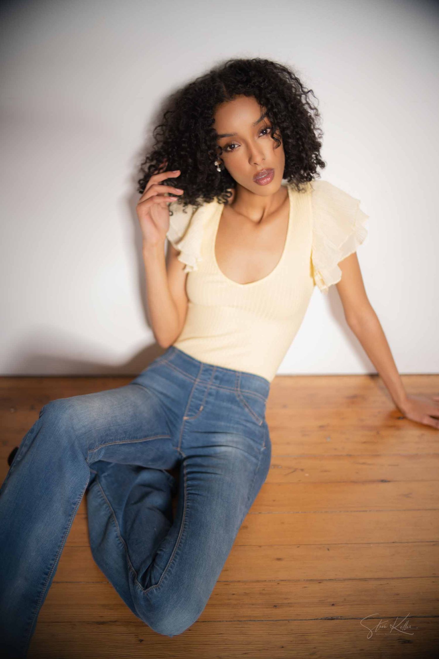 A series of five artistic portraits showing someone in a peach top and jeans sitting casually on wooden flooring.