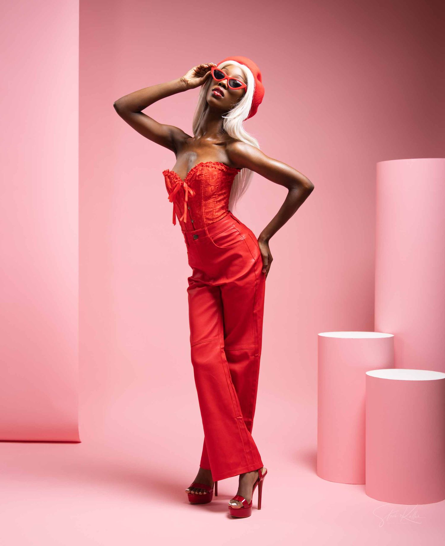 Fashion model in red dress strikes dynamic poses against pink backdrop with white geometric shapes.