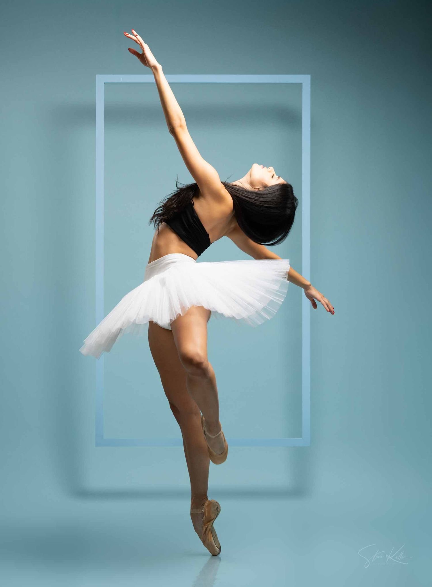 A dancer in white performs a graceful sequence of leaping movements against a soft blue-tinted studio backdrop.