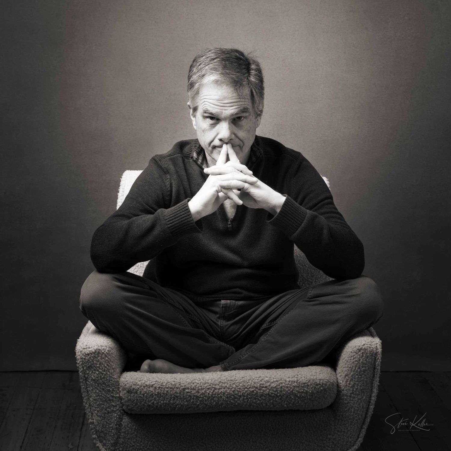 Four black and white photos showing someone in dark clothing sitting in an armchair expressing different emotional states.