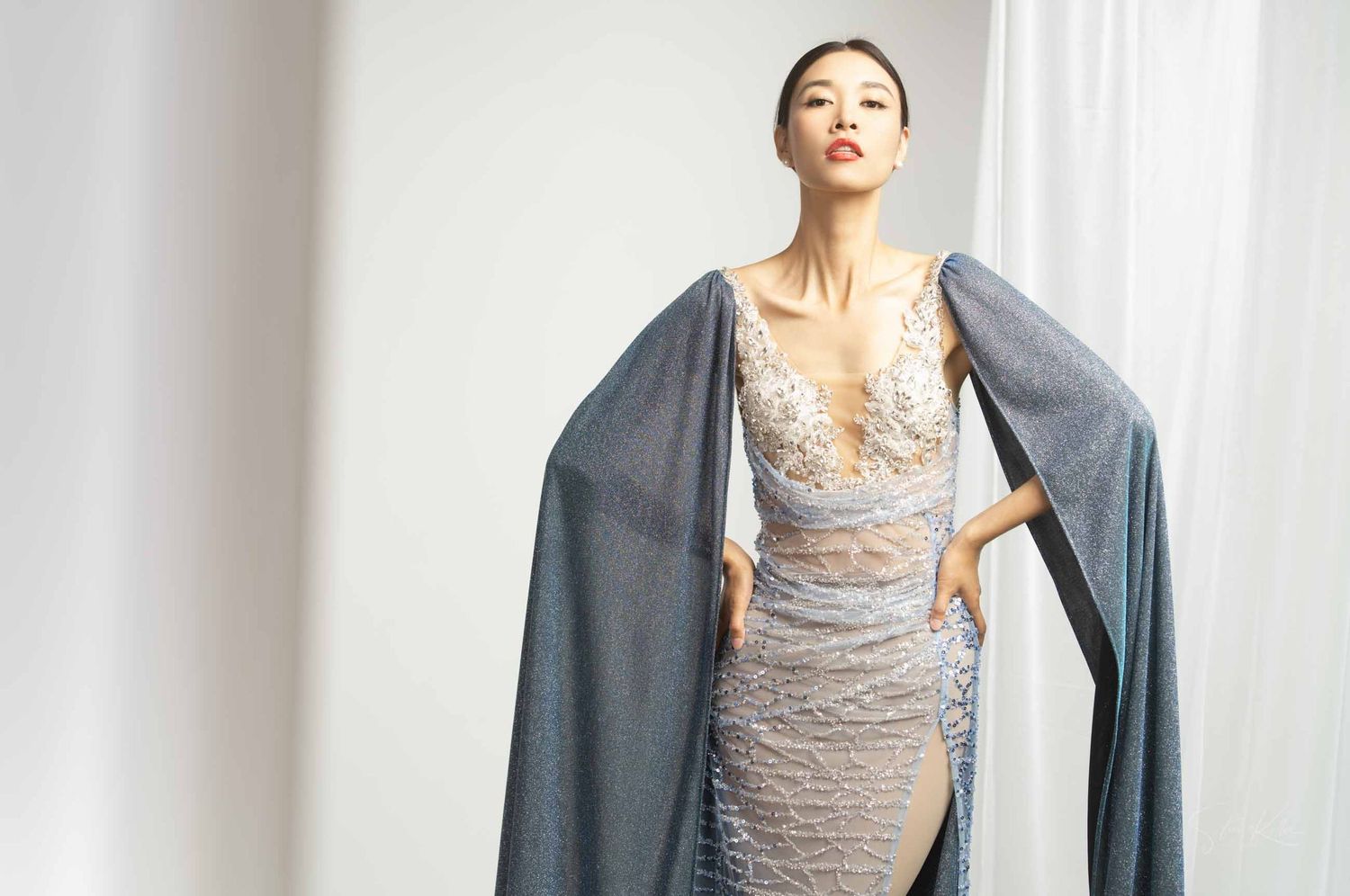 A person wearing a gray cardigan over a lace tank top poses in a bright interior setting.