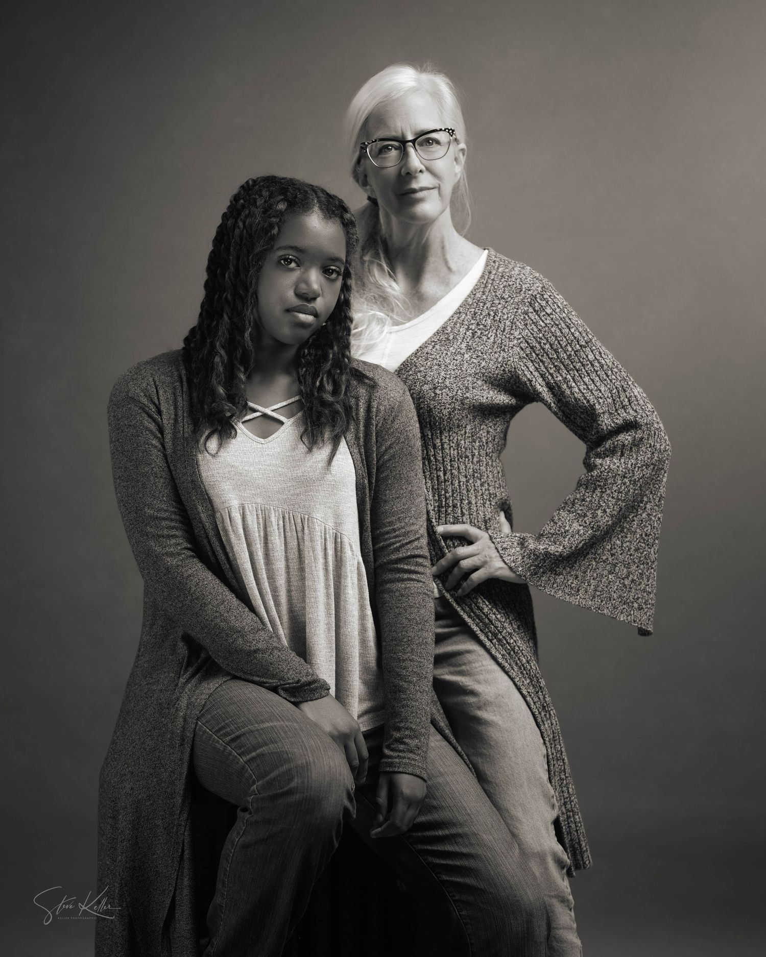 Studio portrait of two people in gray sweaters posing with confident stances.
