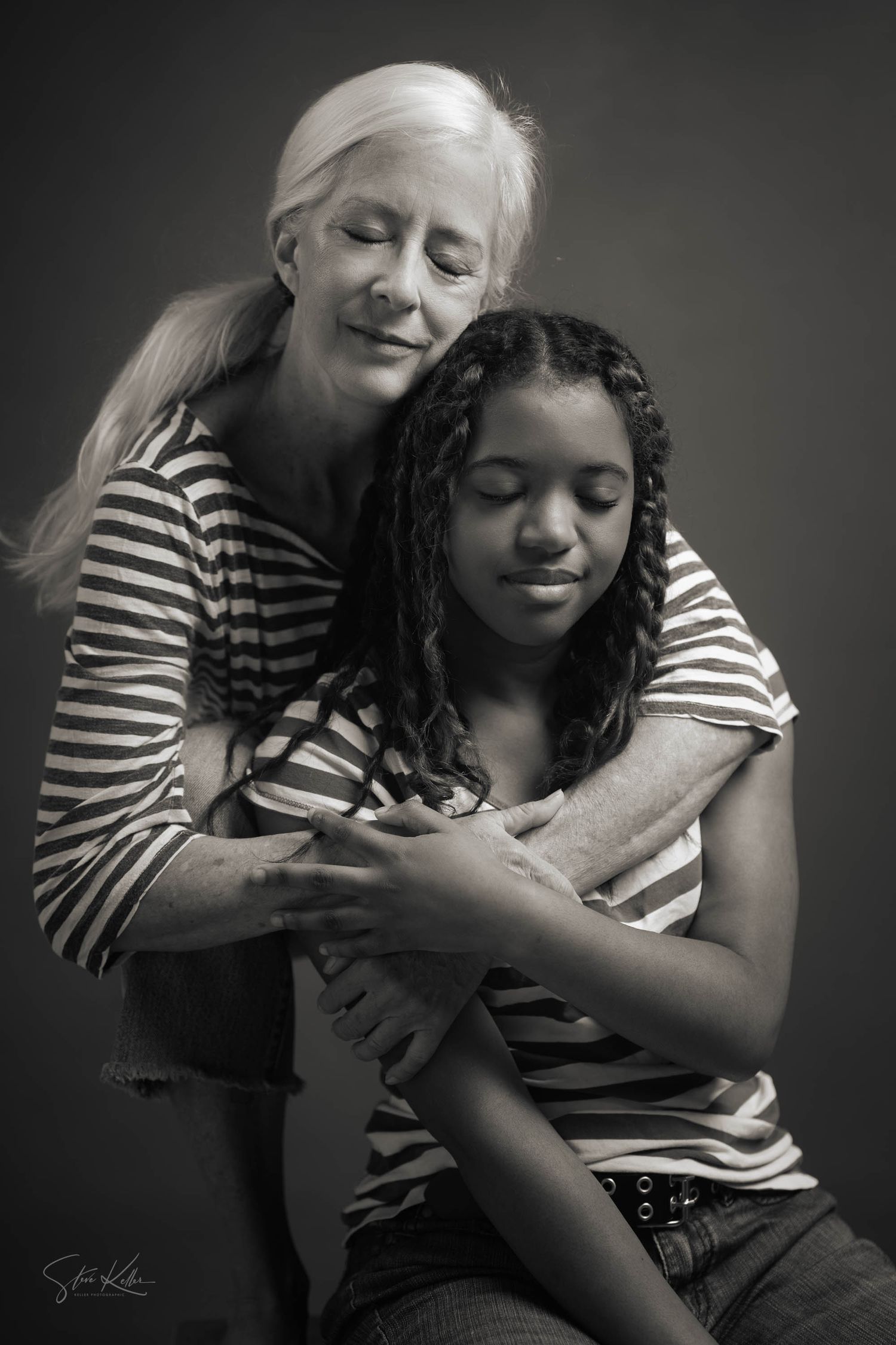 Intimate black and white portrait showing tender embrace in matching striped shirts.