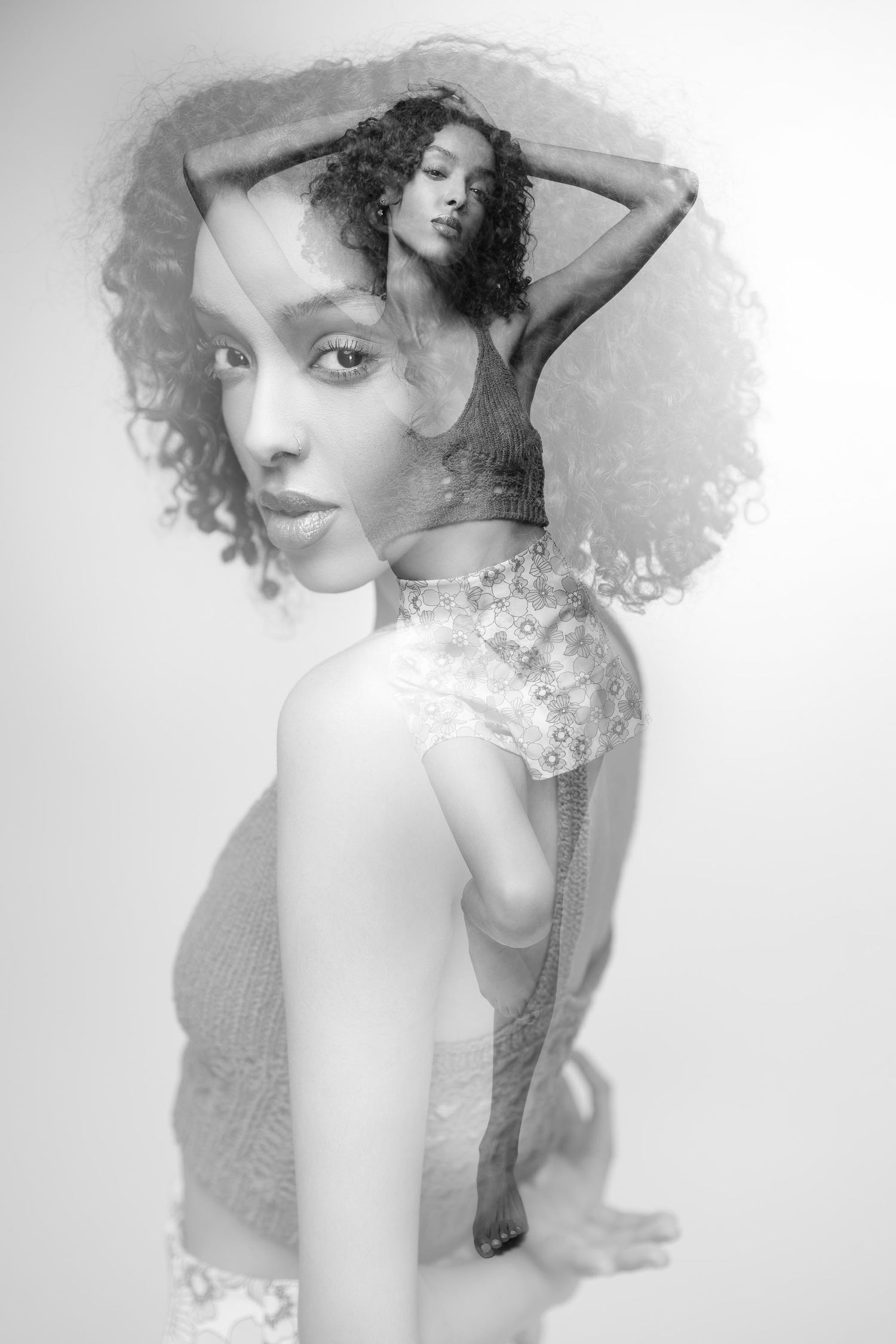 Black and white double exposure portrait of a young woman with curly hair in artistic layered photography.