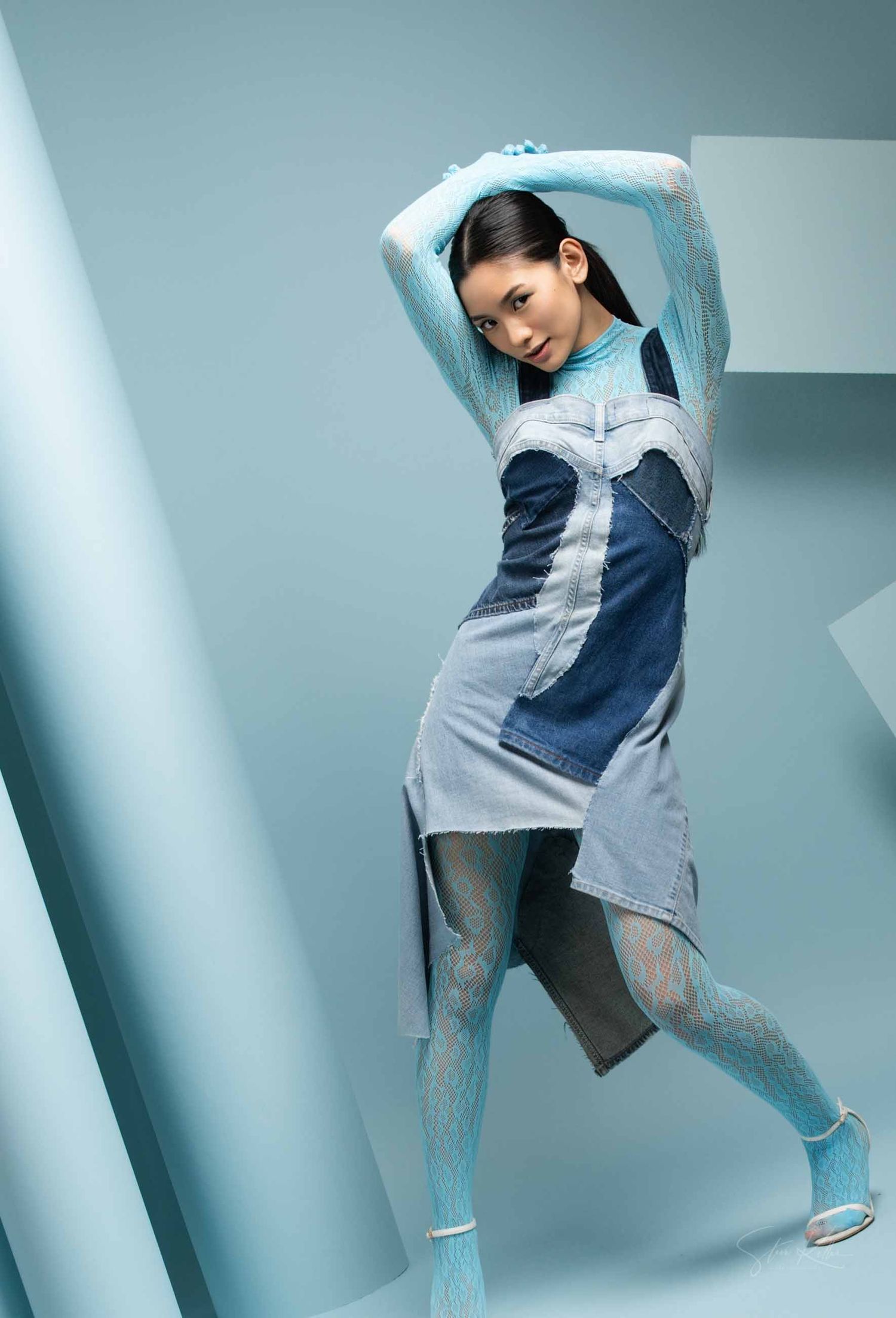 Fashion model in blue and gray sportswear strikes dynamic poses against light blue studio backdrop.