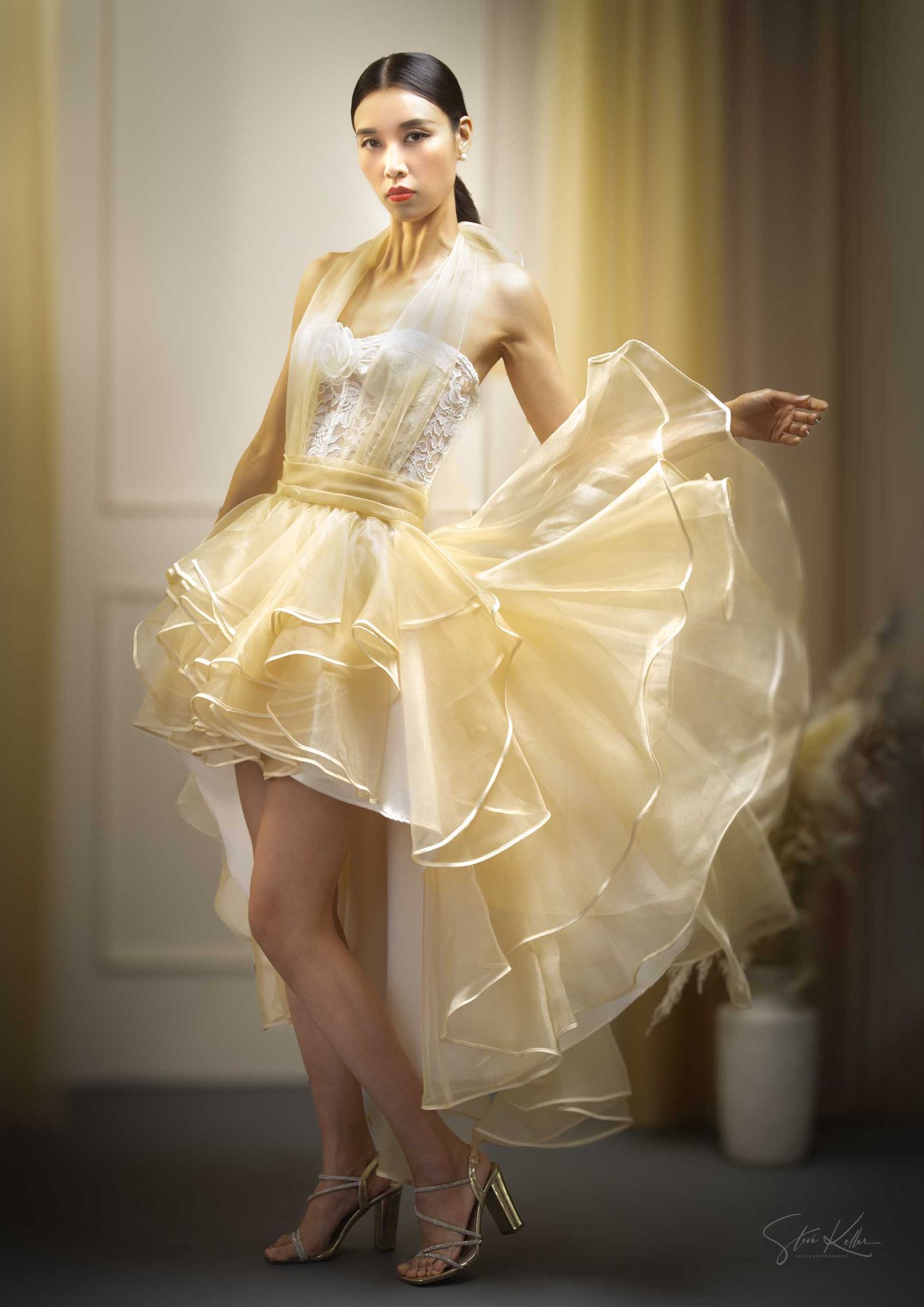 Flowing cream-colored cocktail dress with ruffled organza layers captured in dynamic motion.