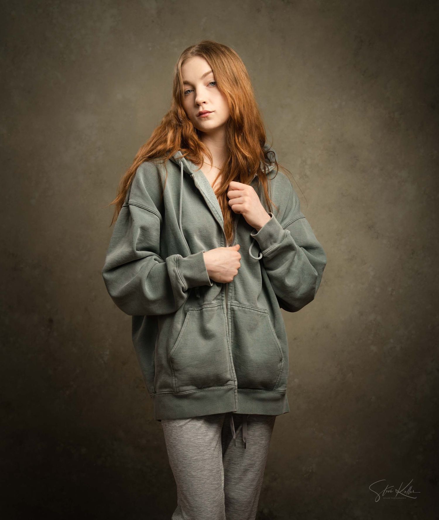 Person modeling comfortable gray loungewear ensemble stands against dark textured background in studio setting.