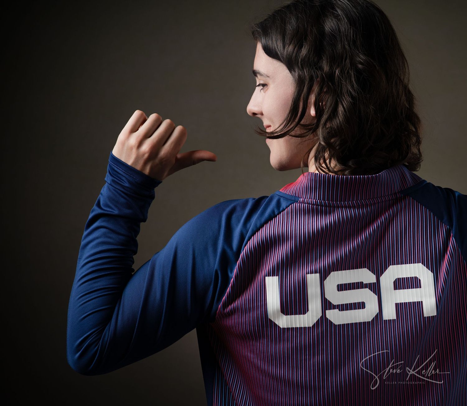 Athletic figure wearing USA team jacket shown in profile view.