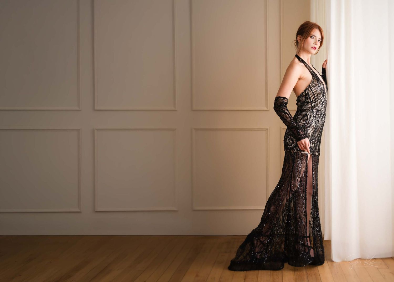 A woman in a black lace dress poses in multiple angles against a white wall in a photo series.