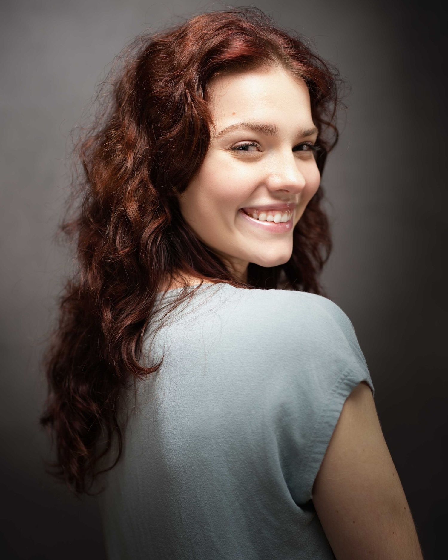 A sequence of photos showing someone with curly dark hair turning and smiling against a gray backdrop.