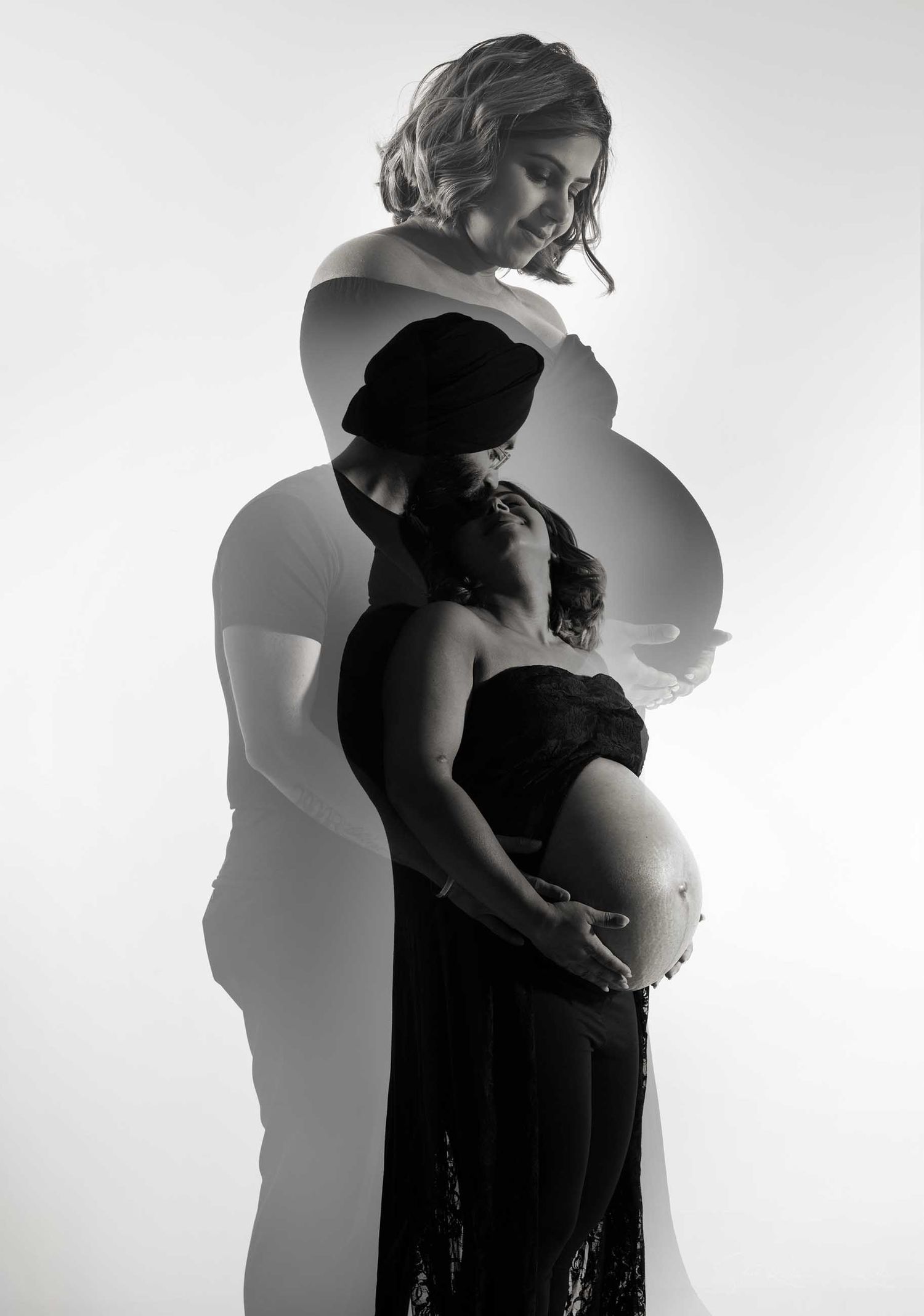 Black and white double exposure maternity photo of pregnant couple embracing, artistic silhouette portrait.