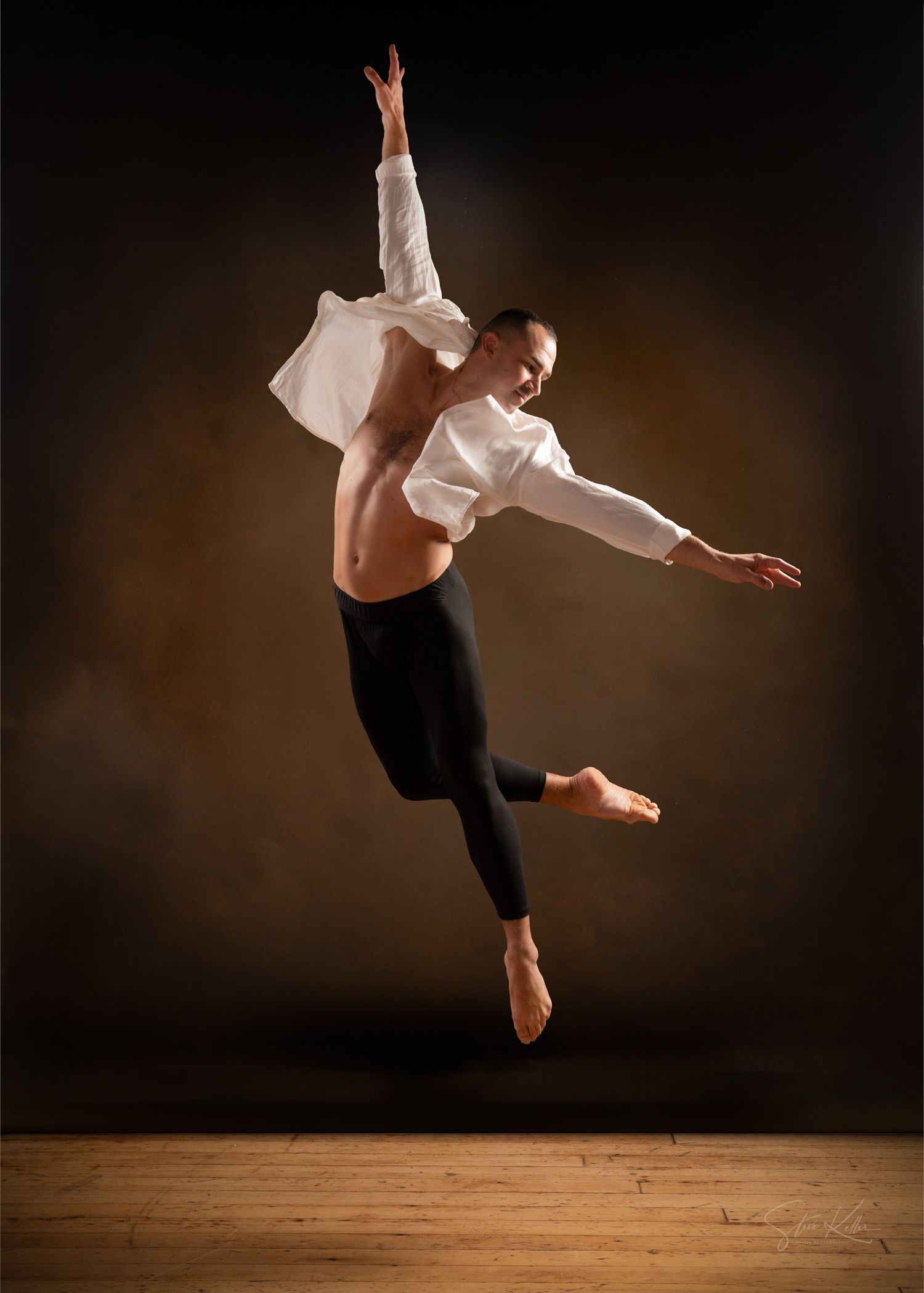 A dancer performs a graceful leap sequence in silhouette against a dark background on a wooden floor.