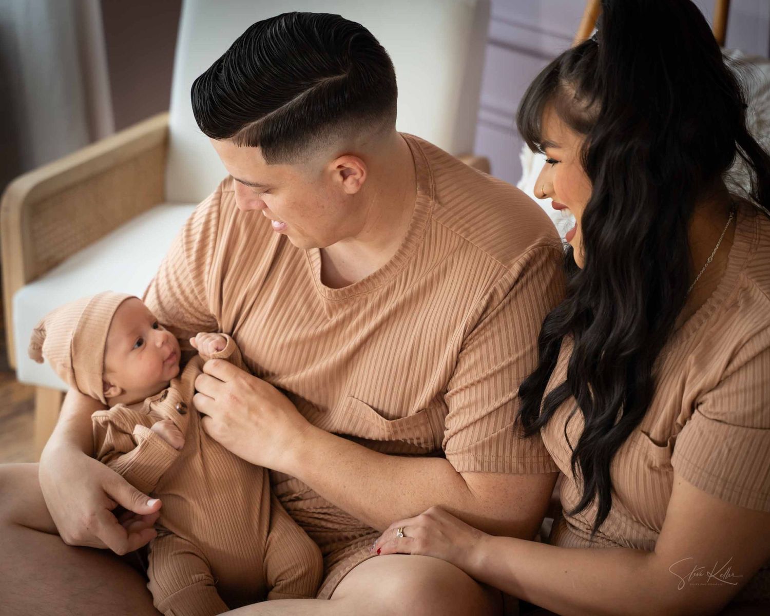 Mother in beige sweater lovingly holds and nurtures newborn baby in intimate breastfeeding photography series.