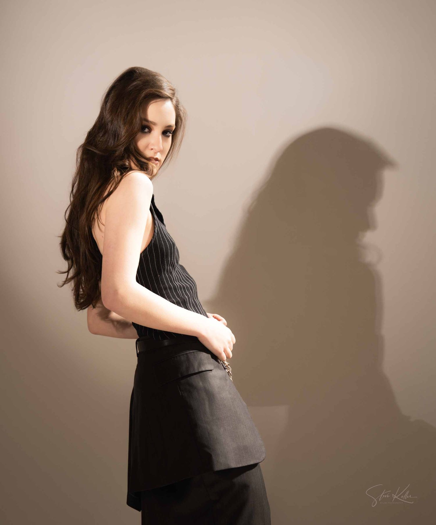 Fashion portrait series showing dynamic poses in a black dress against a neutral studio backdrop with dramatic shadows.
