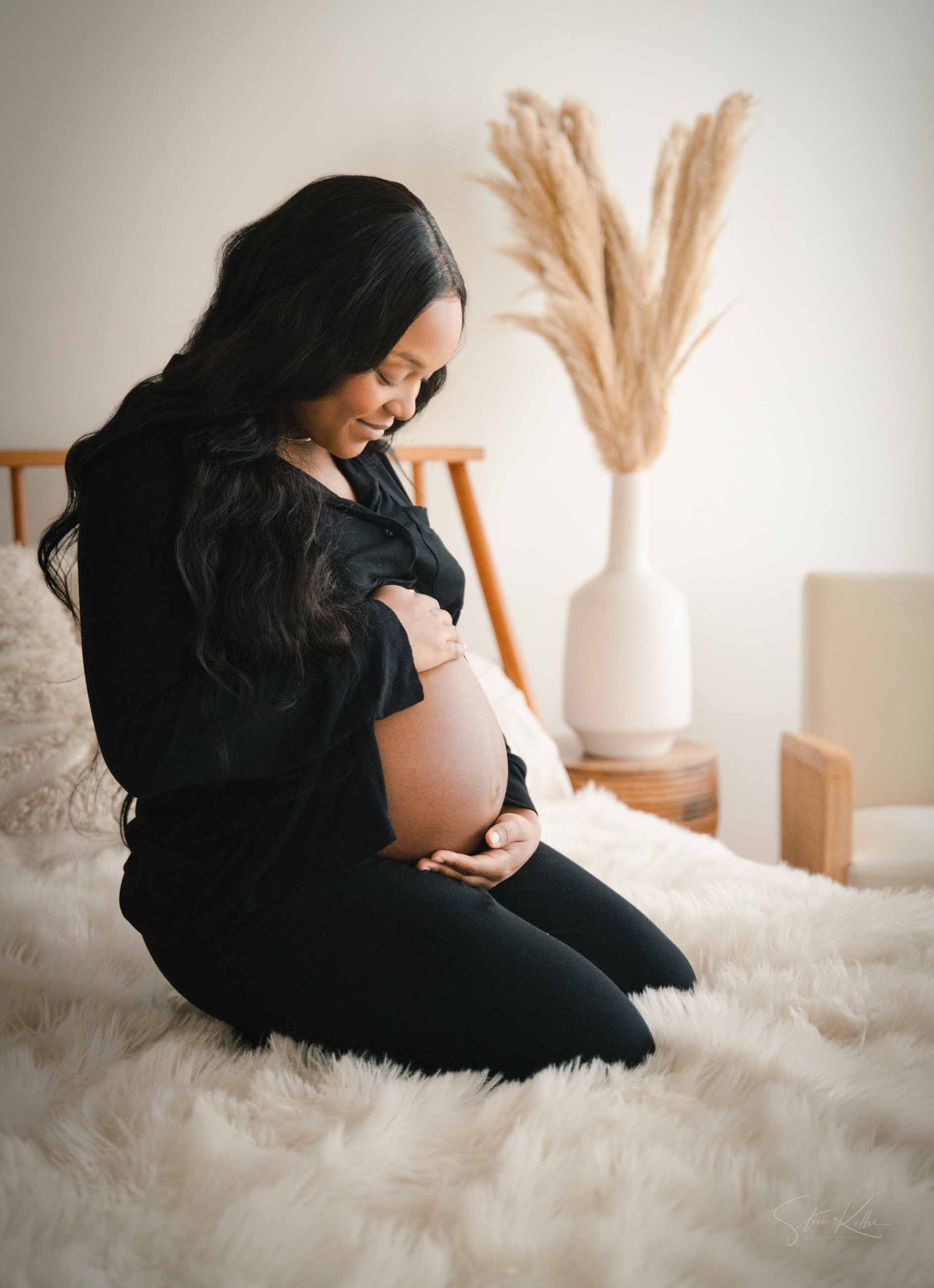 A series of maternity photos showing a pregnant woman in black dress resting on white fur backdrop with pampas grass decor.