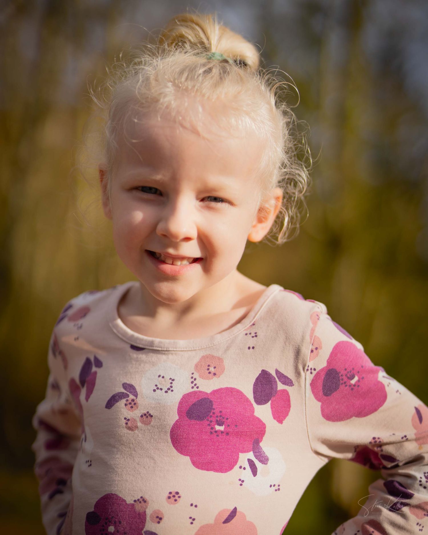 A joyful expression captured in a series of outdoor portraits wearing a pink butterfly print shirt.