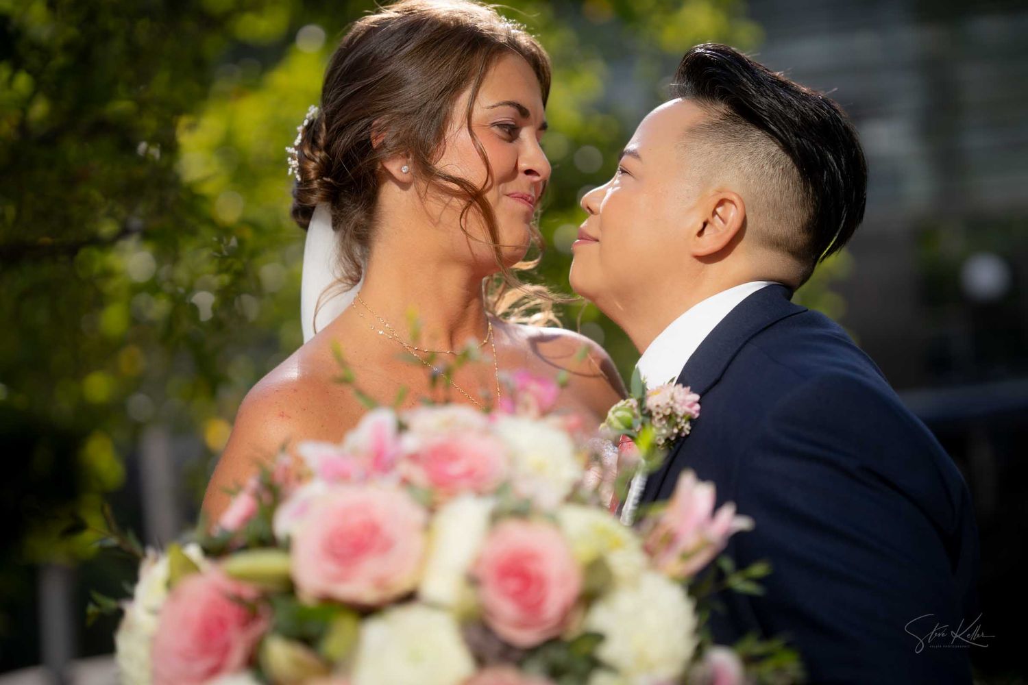 Couple sharing a romantic moment at their wedding, with a beautiful pink and white floral bouquet in the foreground.