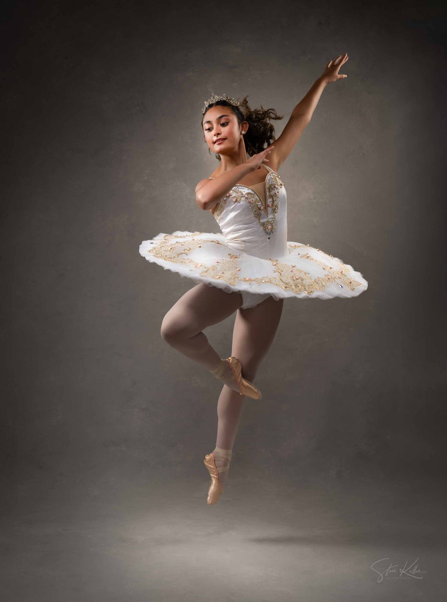 Ballerina in white tutu performs elegant arabesque poses against dark background in dramatic lighting.
